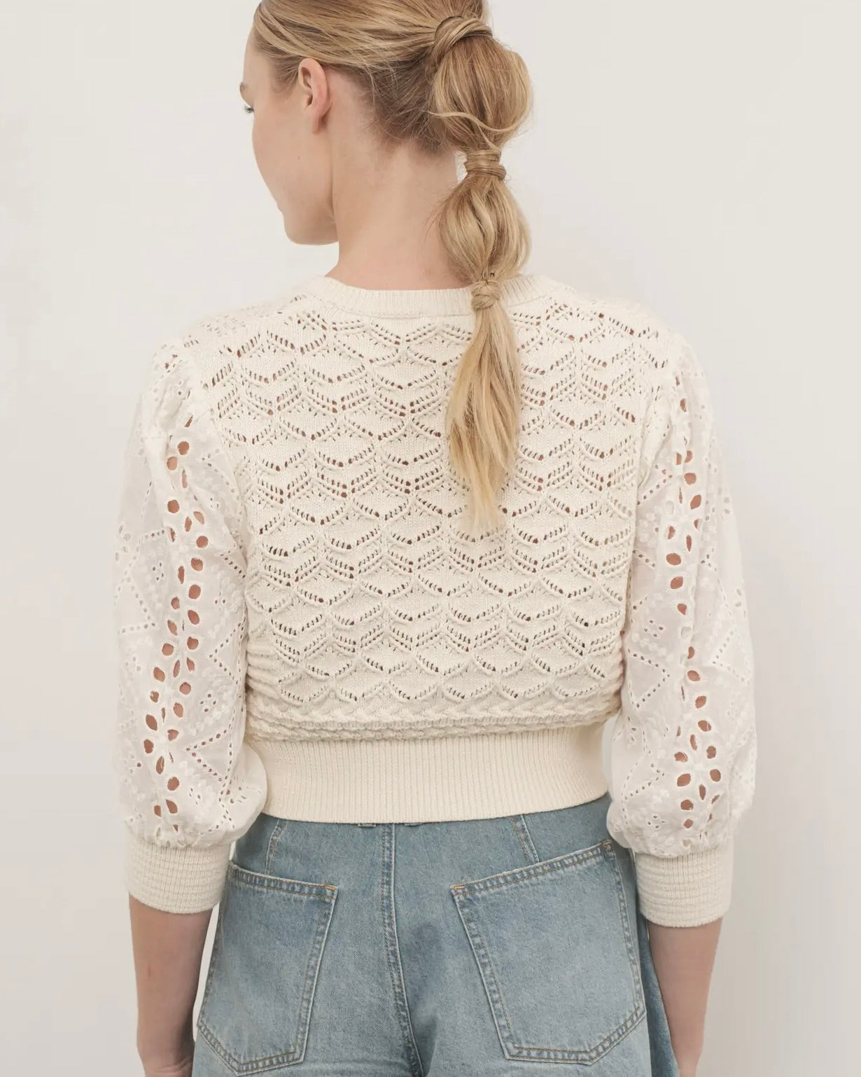 Back view of a model wearing the Hendry 3/4 sleeve cardigan with jeans standing in front of a white background