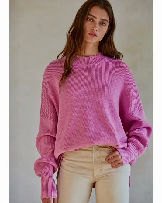 Model wearing By Together Lilac Pink Chunky East Street Pullover sweater wearing cream color pants on a gray background