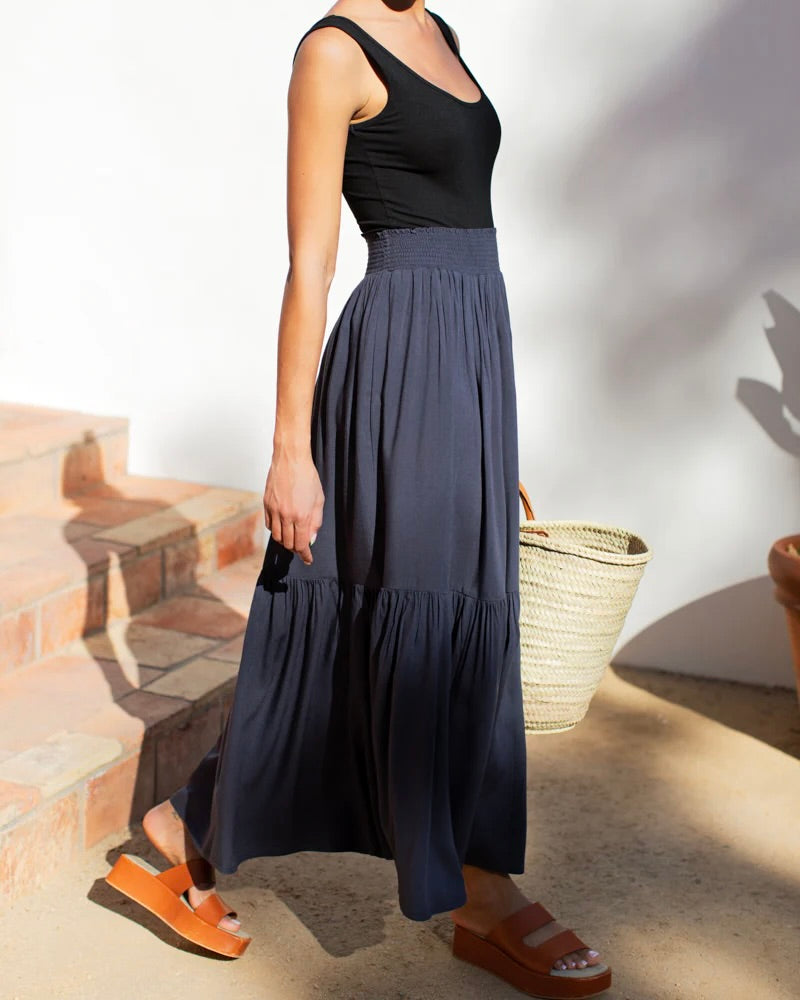 Model wearing Emerson Fry Shirred skirt in midnight blue wearing black tank and brown sandals 