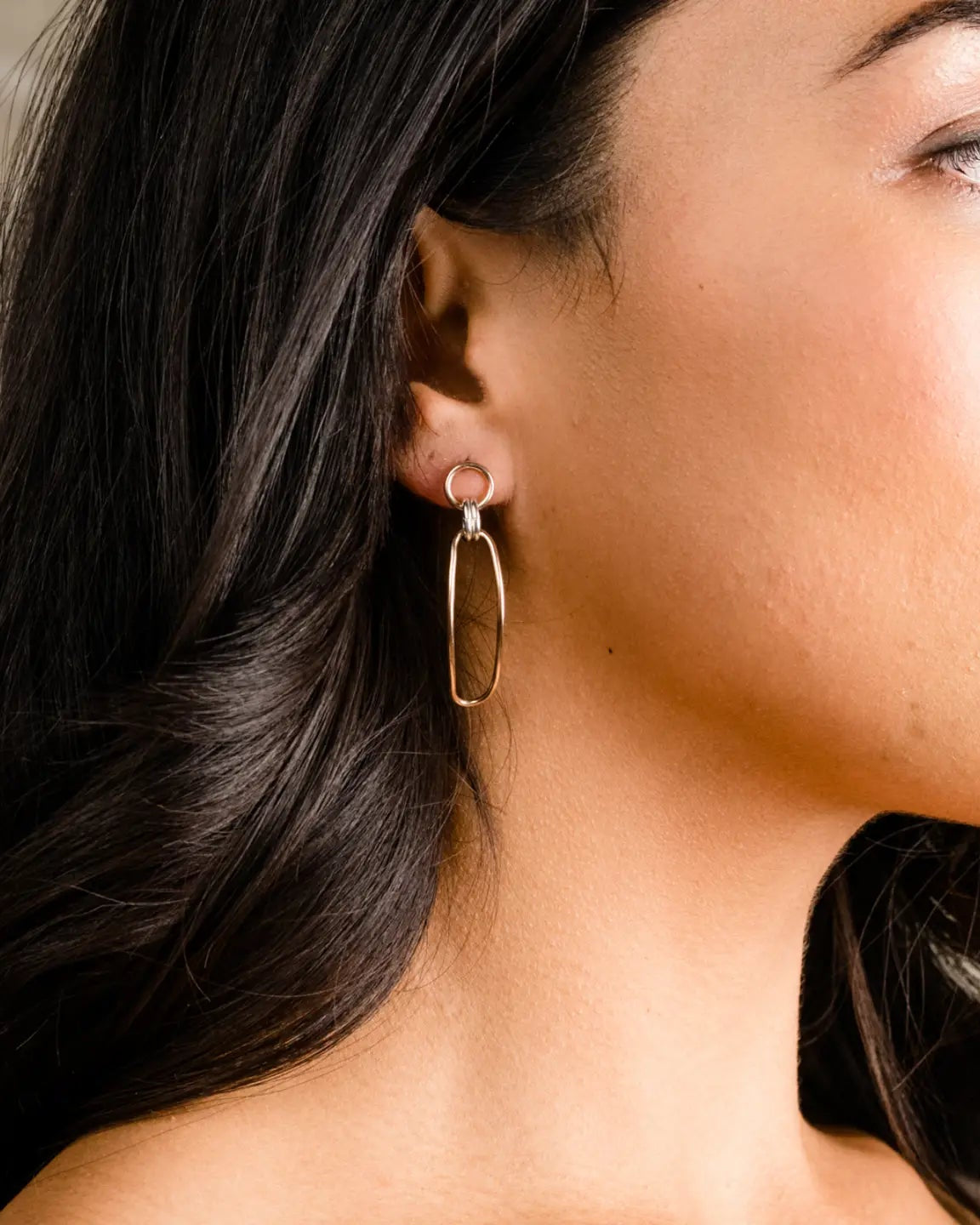 Photo of model from the side wearing the Able Date Night Two-Tone Drop Earrings