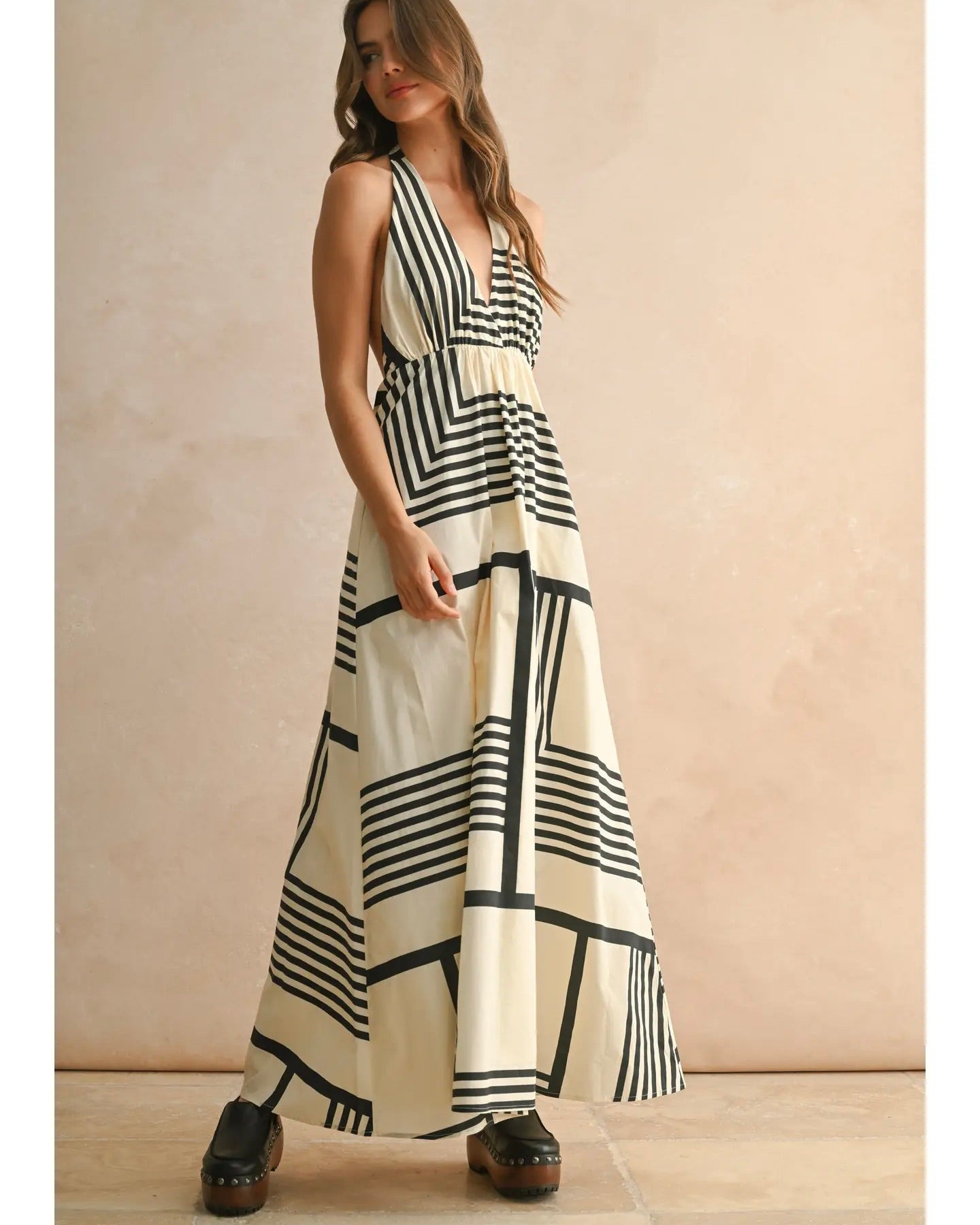 Model is wearing MIOU MUSE Geo Print Halter Dress on a beige background.