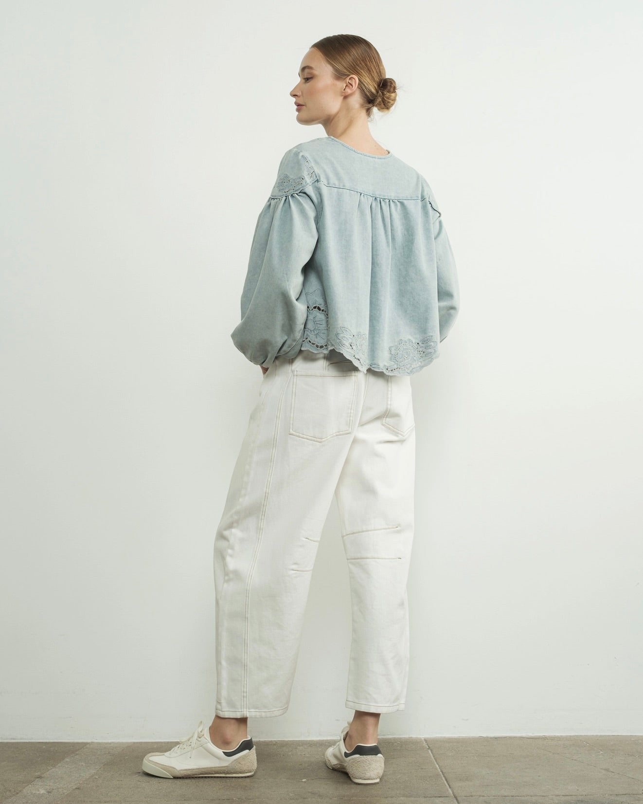 Aaron and amber denim floral embroidery blouse, woman wearing puff light blue denim top, back of top in front of white wall, white jeans, woman standing, spring summer top