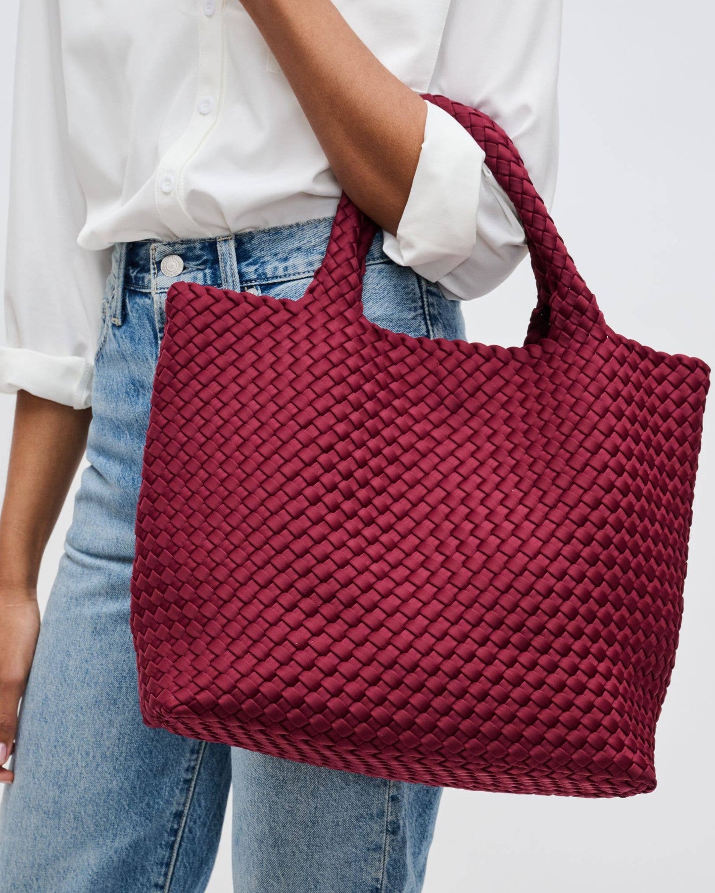 Person holding a red woven handbag against a plain background