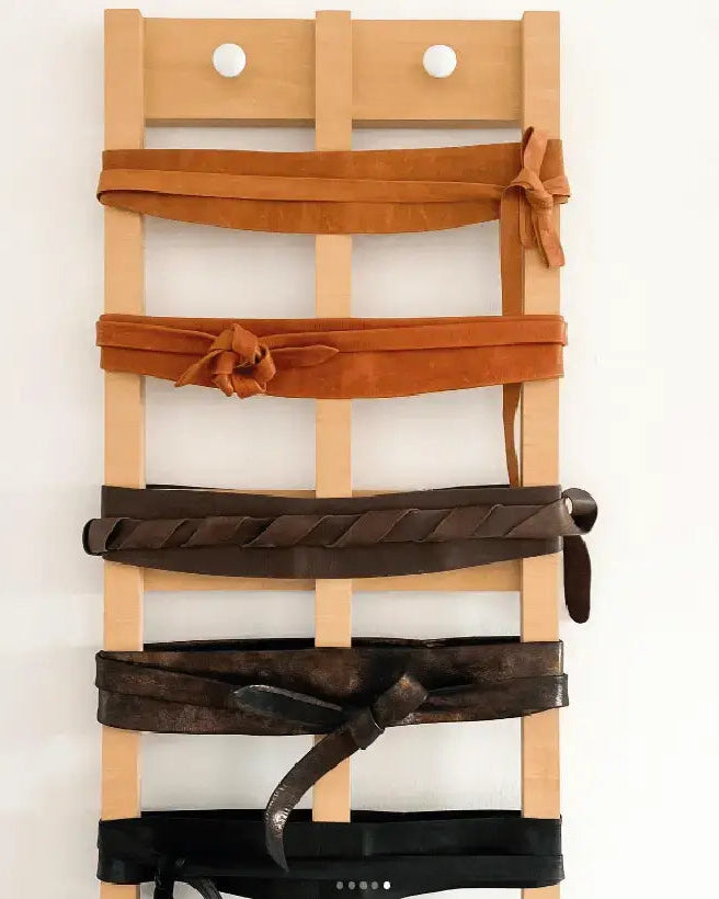 Wooden ladder with leather belts against a white background