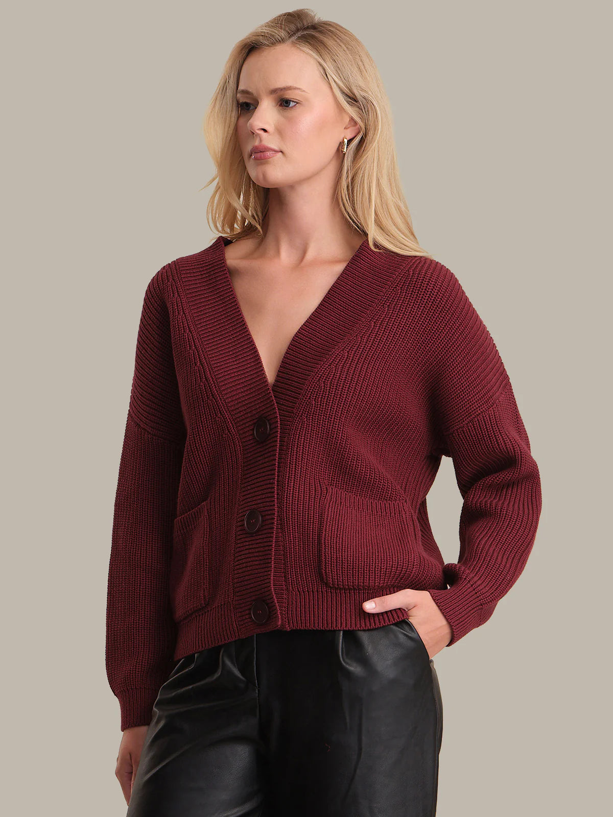 Woman wearing a burgundy cardigan against a neutral background
