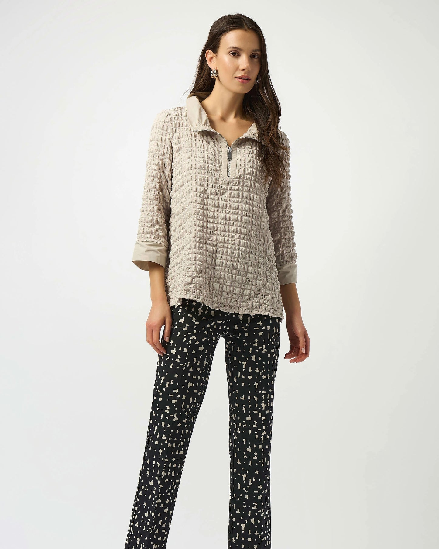 Model is wearing Joseph Ribkoff Bubble Jacquard A-Line Top in color moonstone with tan and black pants on a white background