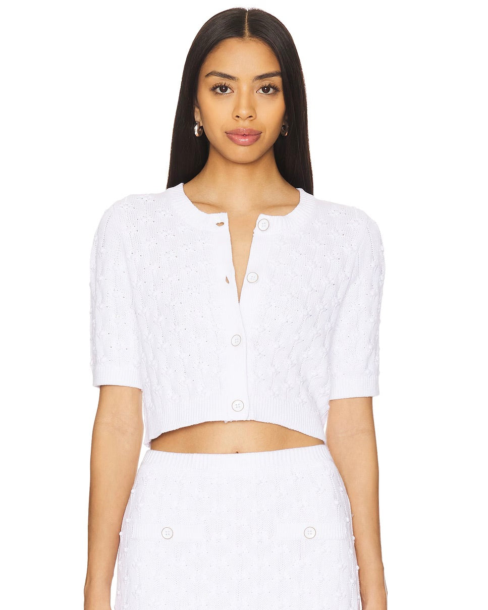 Front view of a model wearing the 525 America Brenda cropped cardigan in bleach standing in front of a white background