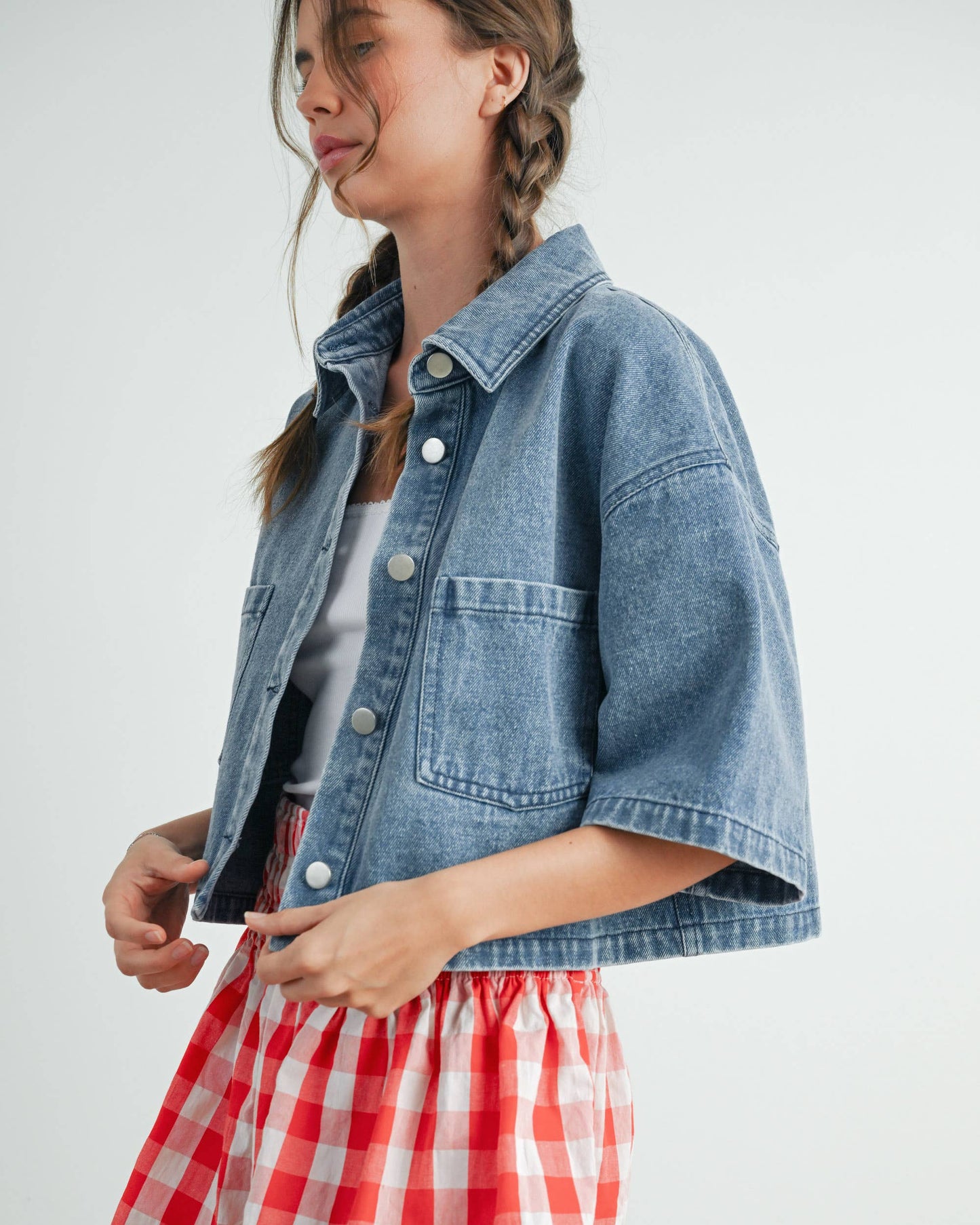 Woman wearing a denim jacket and red checkered skirt on a white background