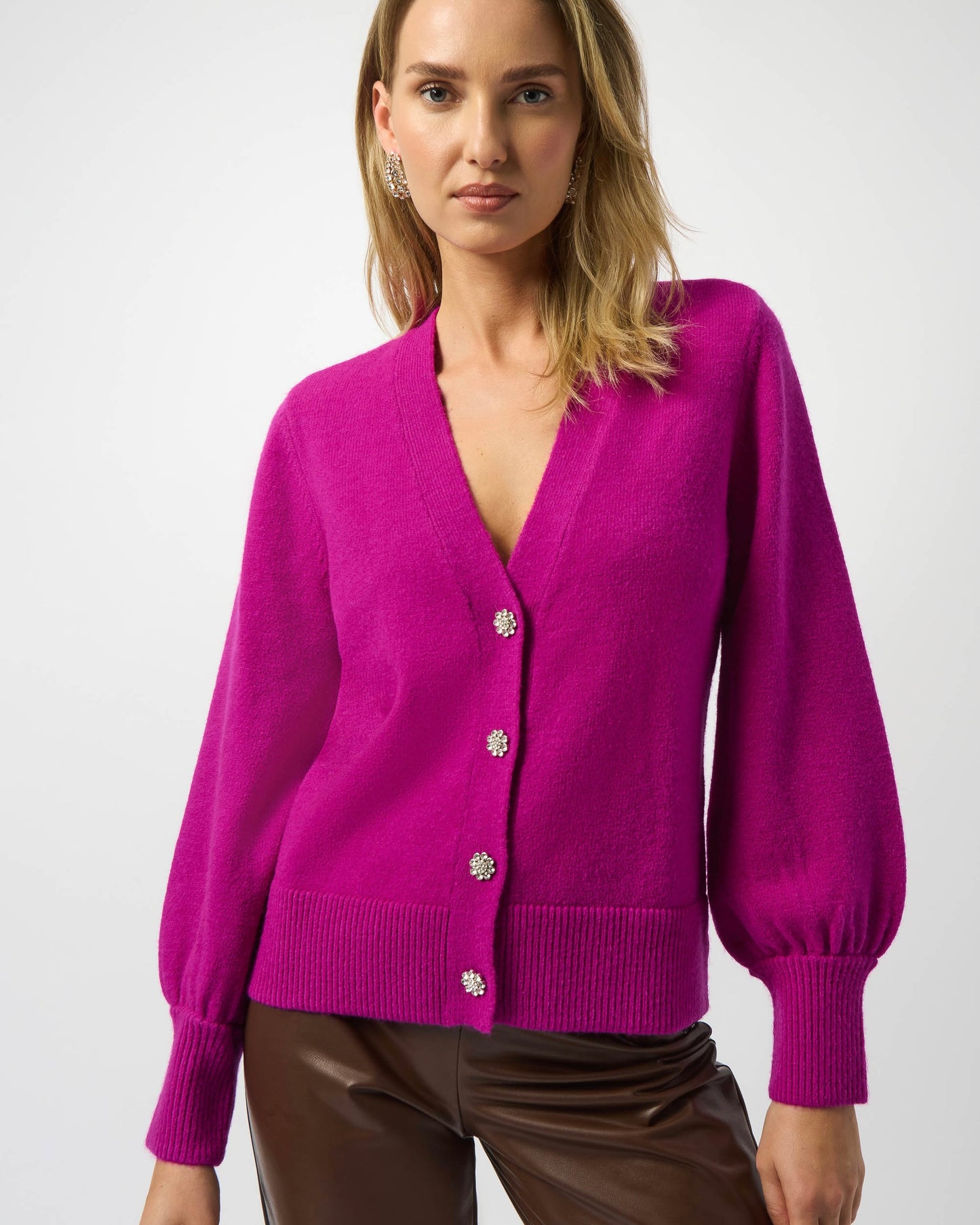 Model is wearing Joseph Ribkoff Sweater Knit Cardigan with Puff Sleeves in color Cosmos paired with brown leather pants on a white background.