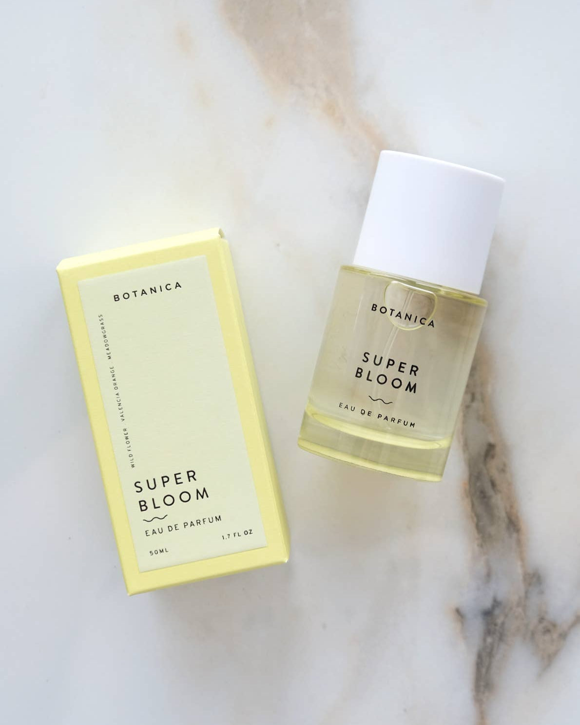 Botanica Super Bloom perfume bottle and packaging on a marble surface