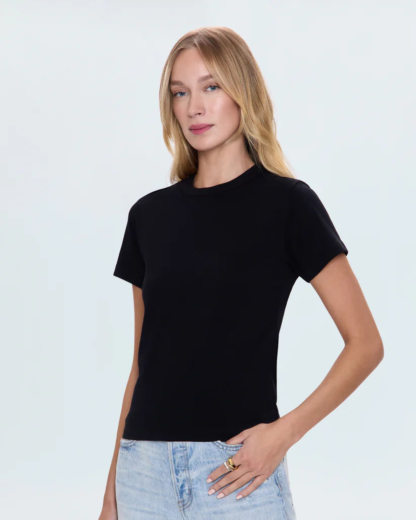 Woman wearing a black t-shirt and light blue jeans against a white background