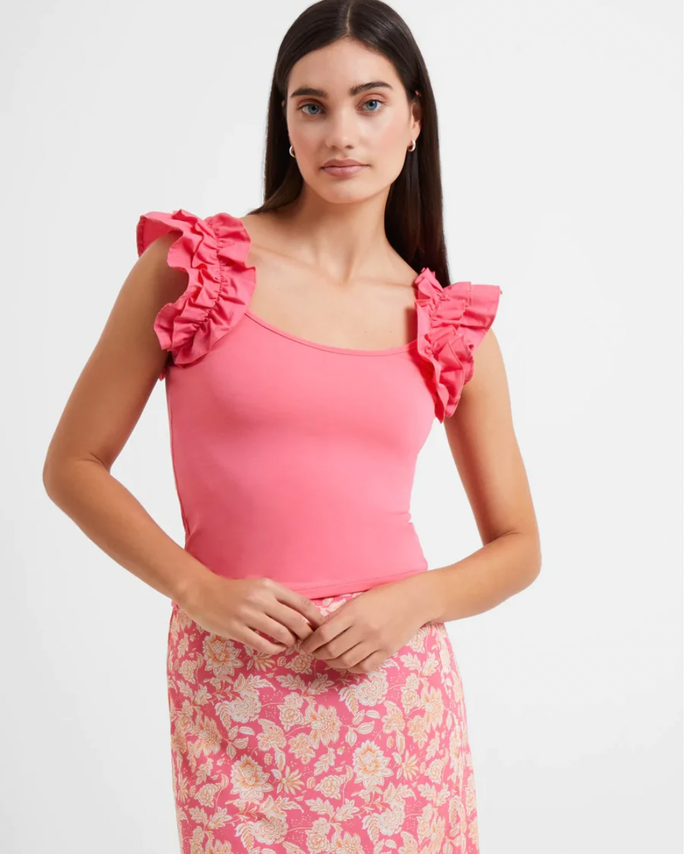 Model Wearing French Connection Rallie Cotton Frill Sleeveless Tee in Camellia Rose Wearing Pink Skirt On A White Background