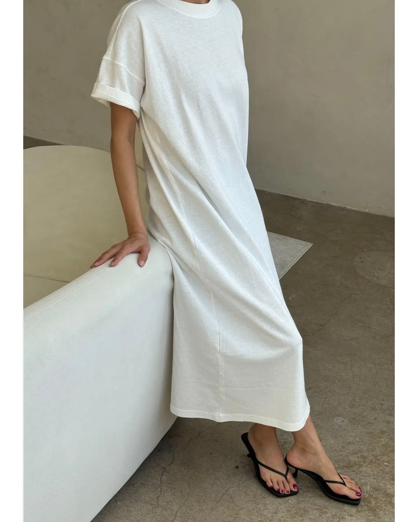 Side view of model leaning on a couch wearing the Le Bon Shoppe Her Dress against a neutral background