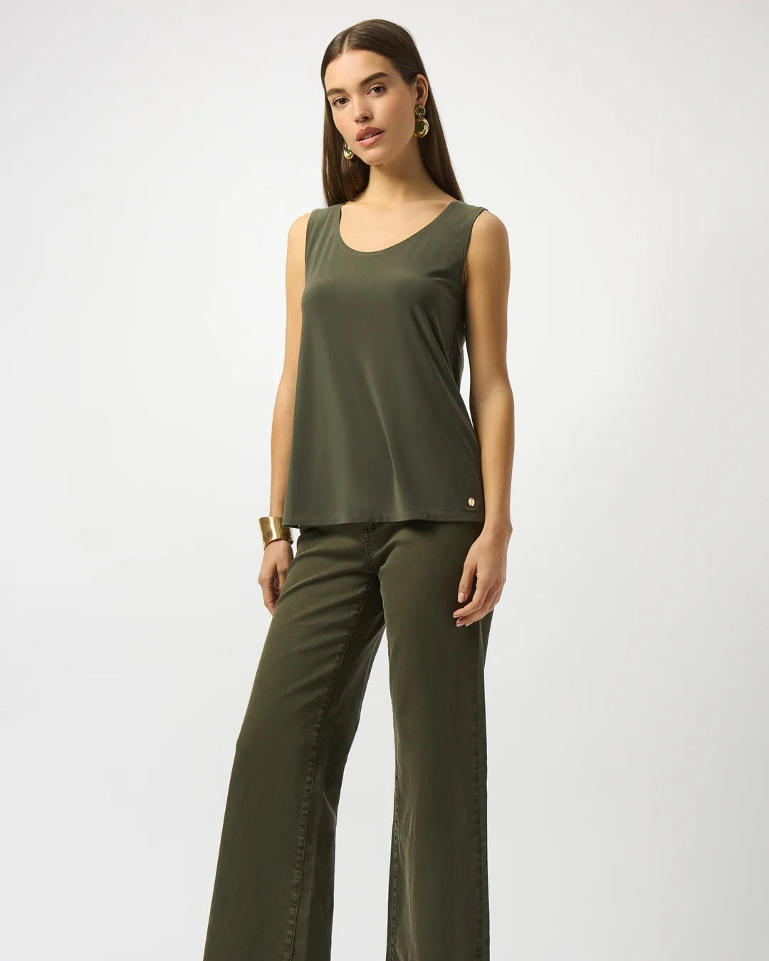 Model is wearing Joseph Ribkoff silky knit scoop neck camisole in color avocado with dark green pants on a white background