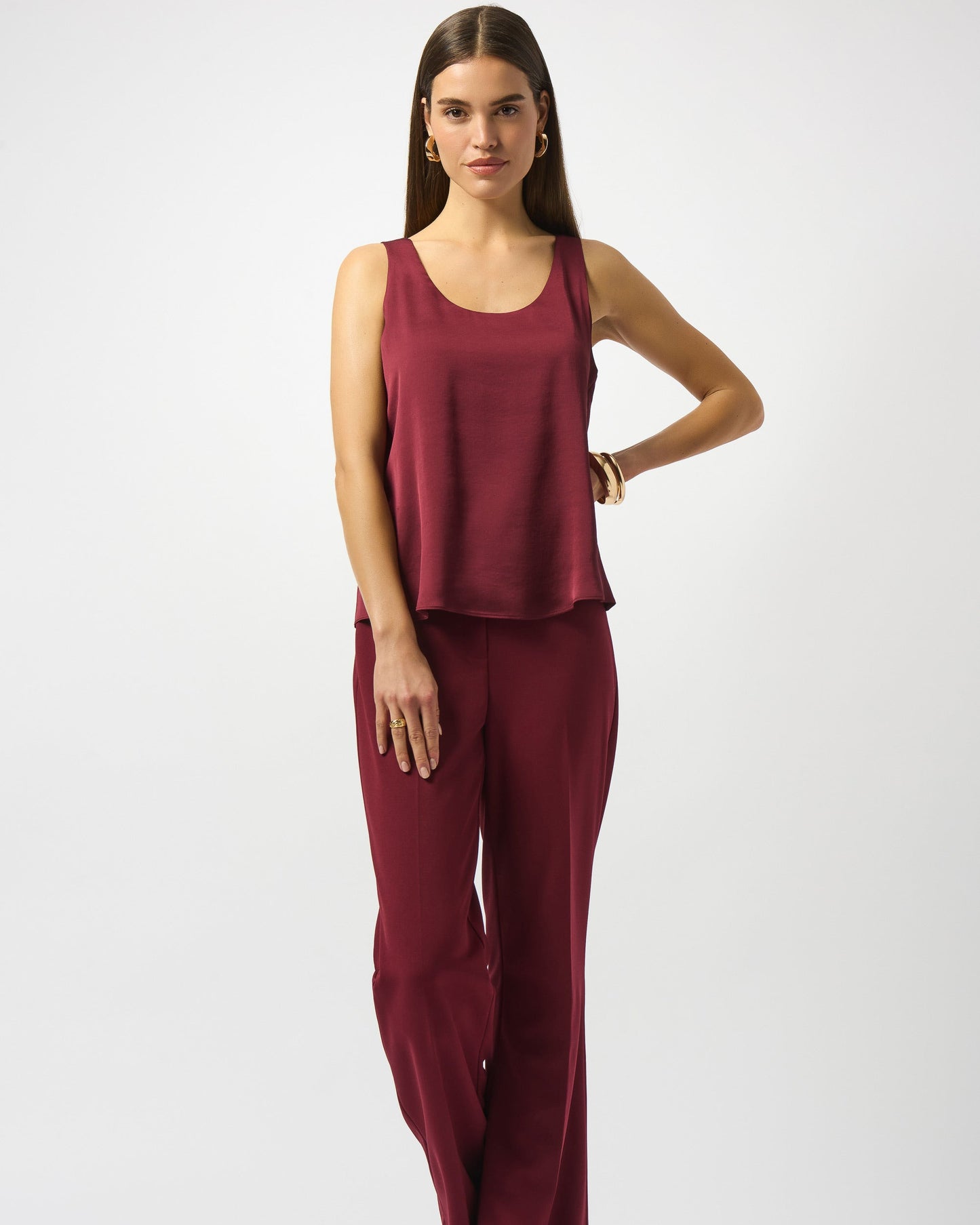 Woman wearing a burgundy sleeveless top and wide-leg pants on a white background