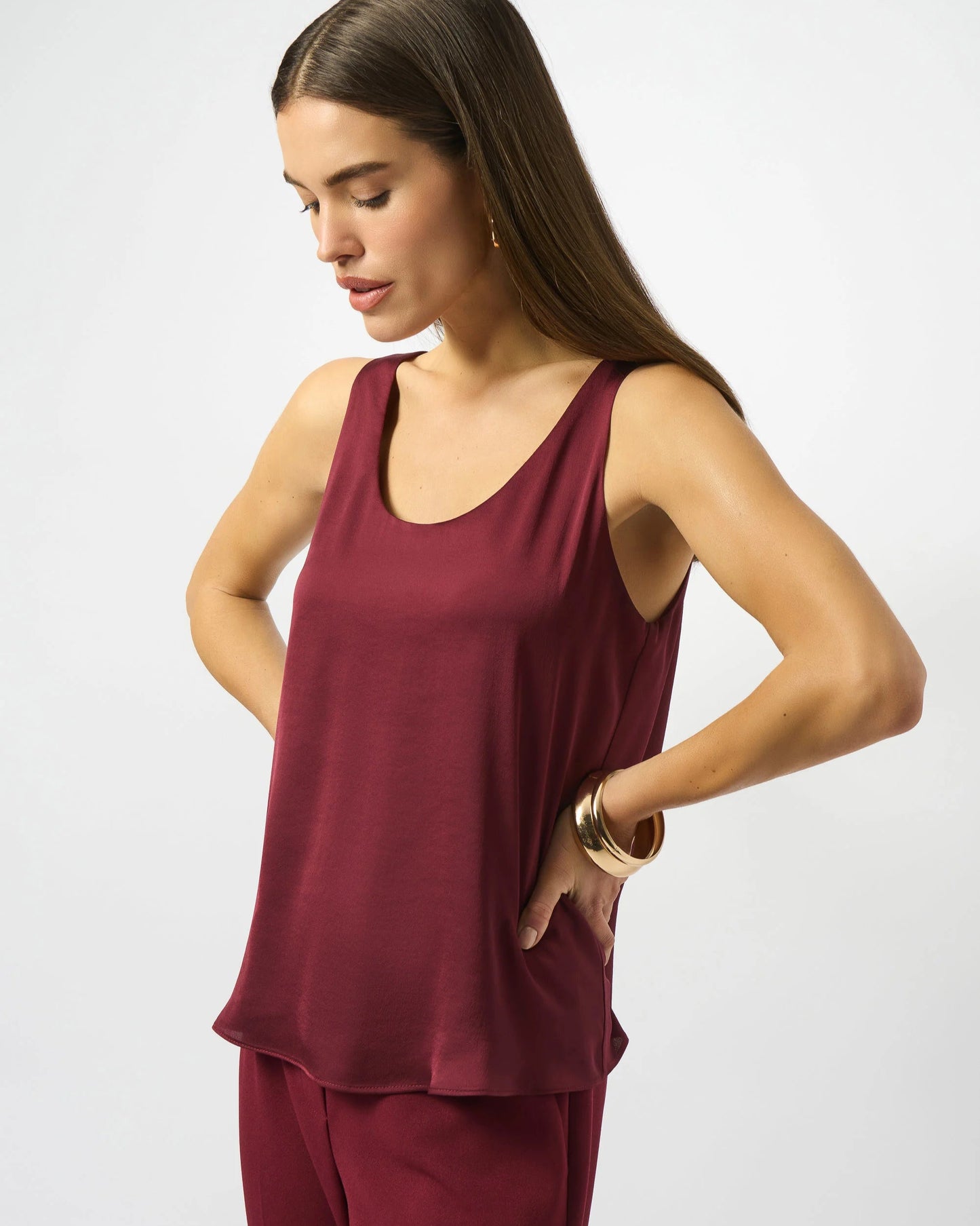 Woman wearing a burgundy sleeveless top and pants on a white background