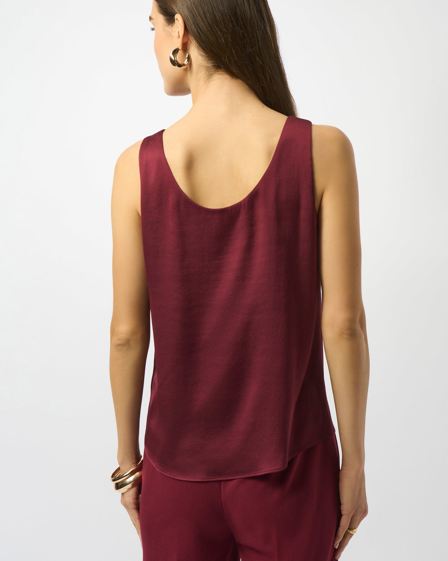 Woman wearing a burgundy sleeveless top and pants on a white background