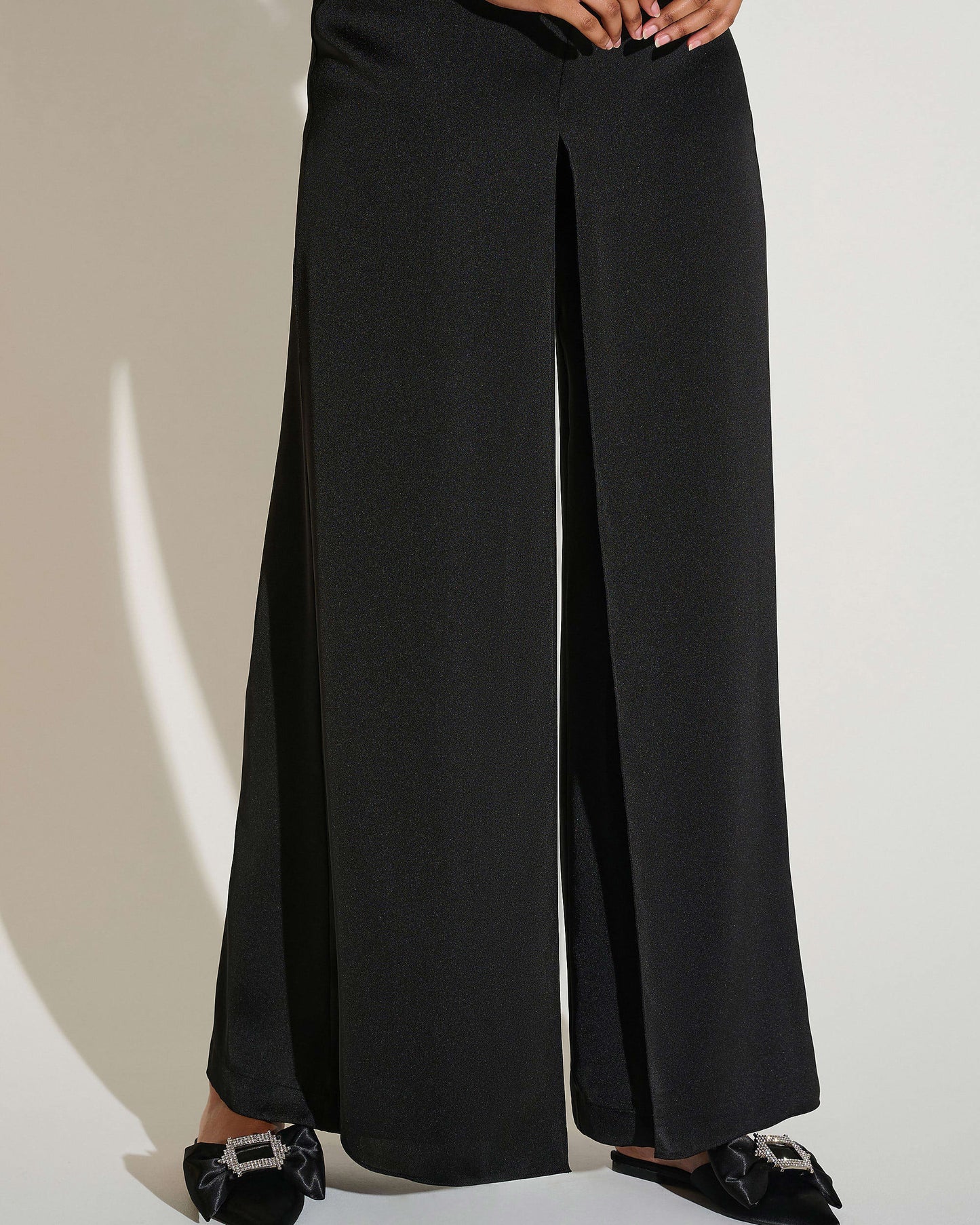 Person wearing black wide-leg pants on a plain background