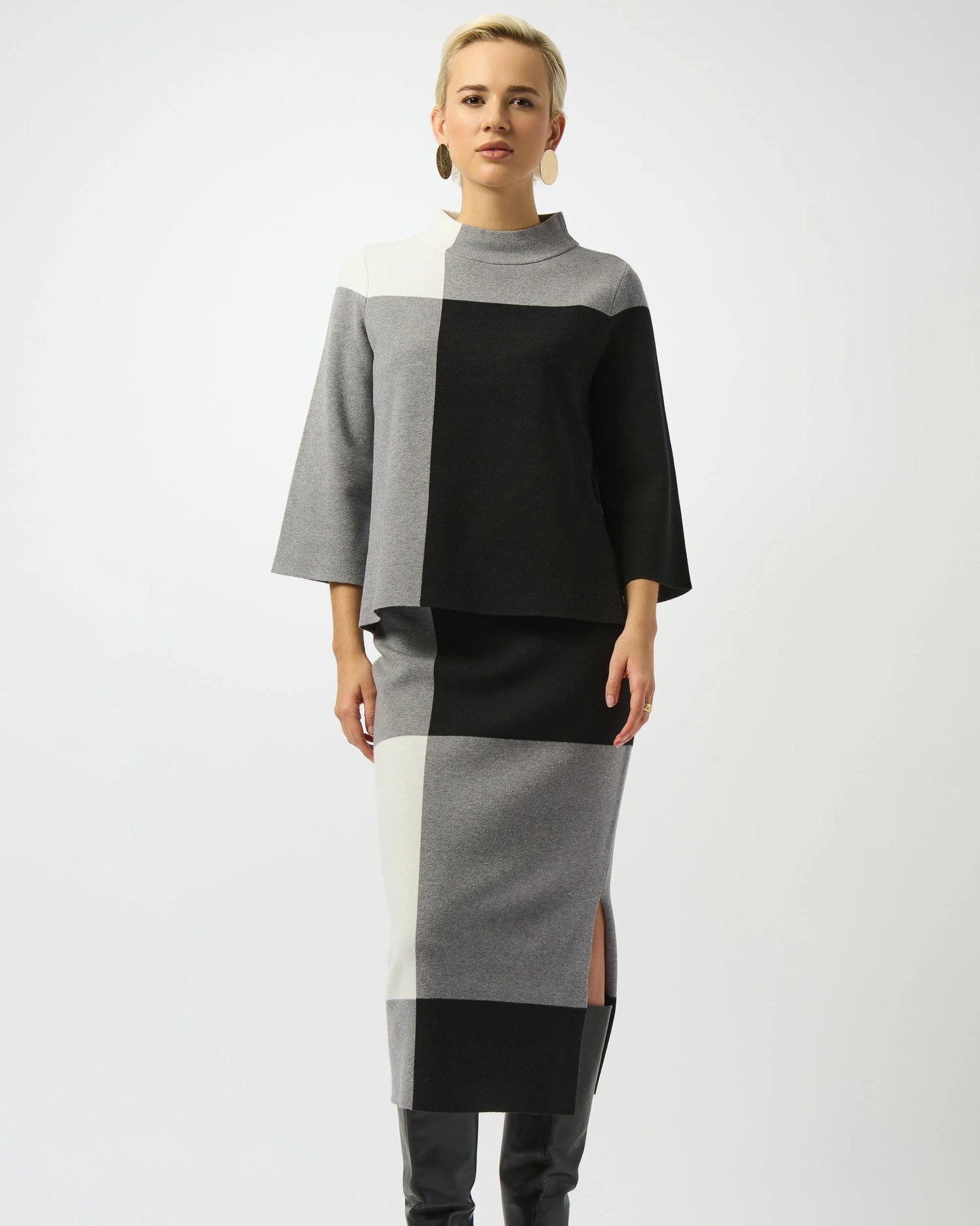 Person wearing a black, gray, and white color-blocked outfit with a cape on a white background