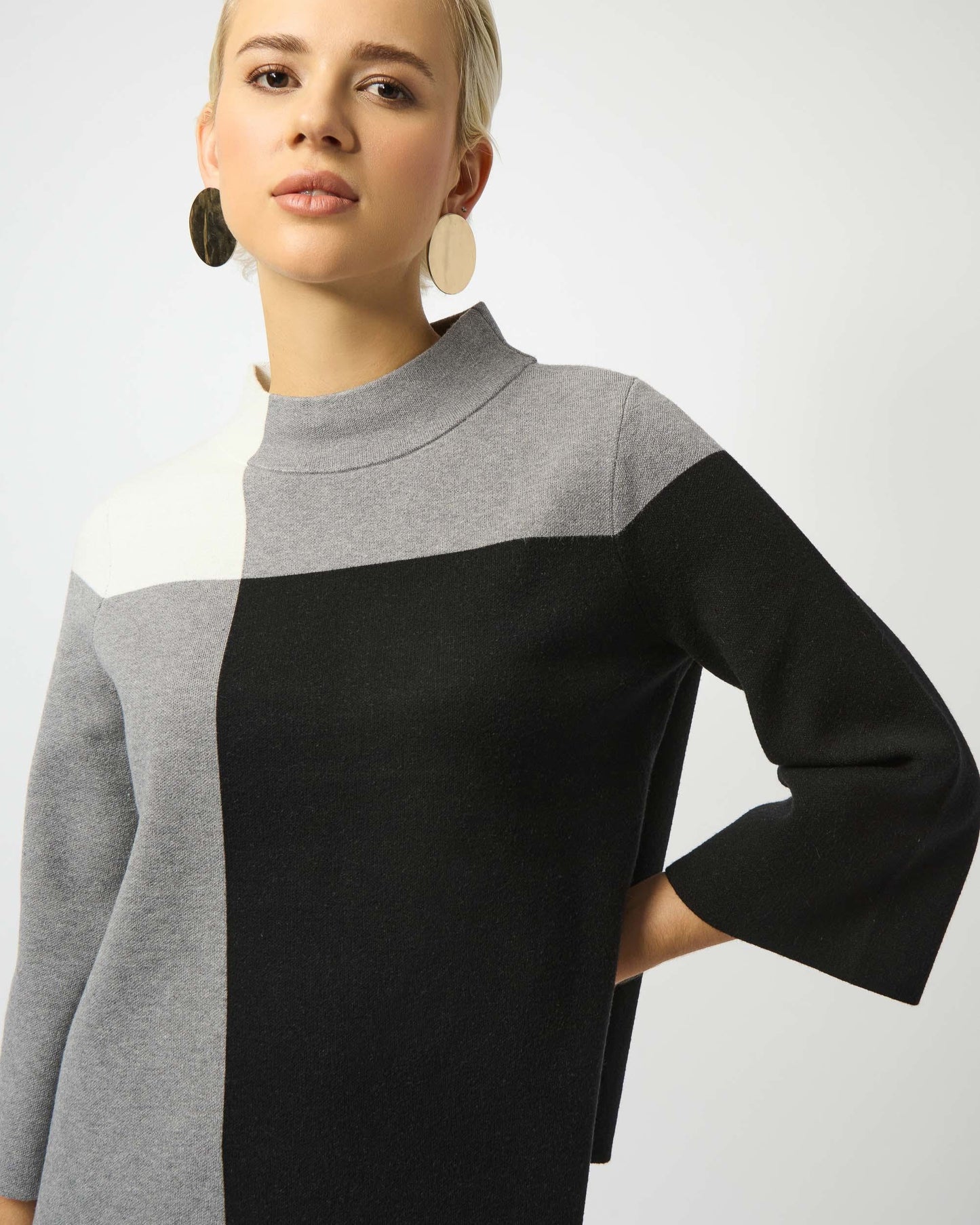 Woman wearing a black and gray color-blocked sweater on a white background