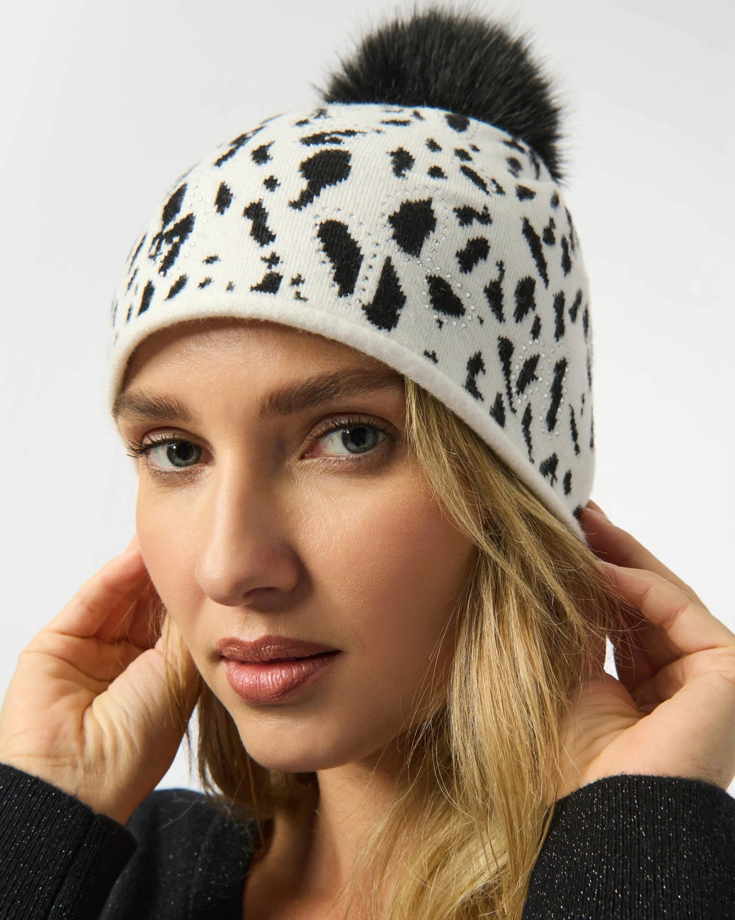 Woman wearing a leopard print beanie with a black pom-pom on a white background