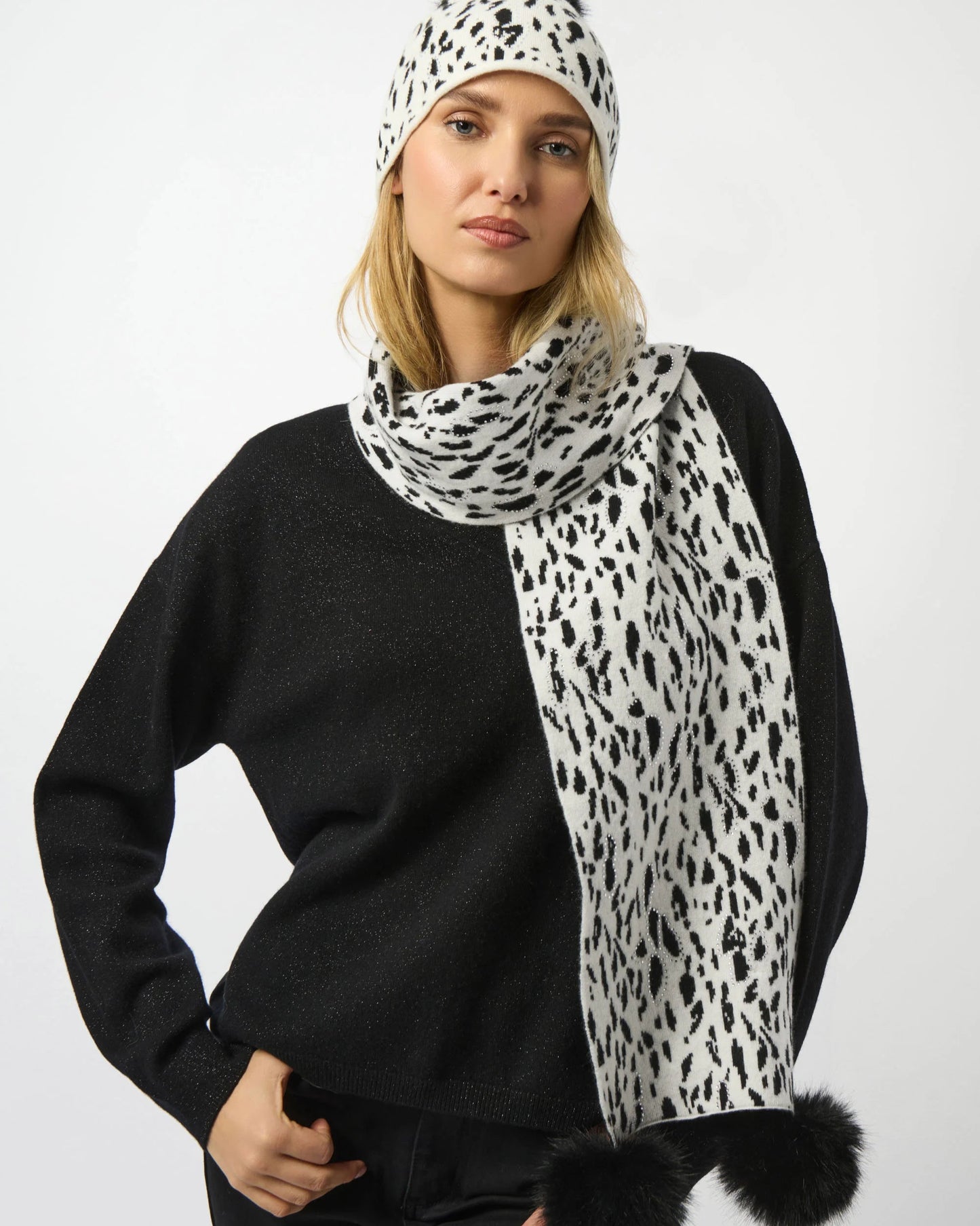 Woman wearing a black sweater and a white scarf with black leopard print pattern on a white background