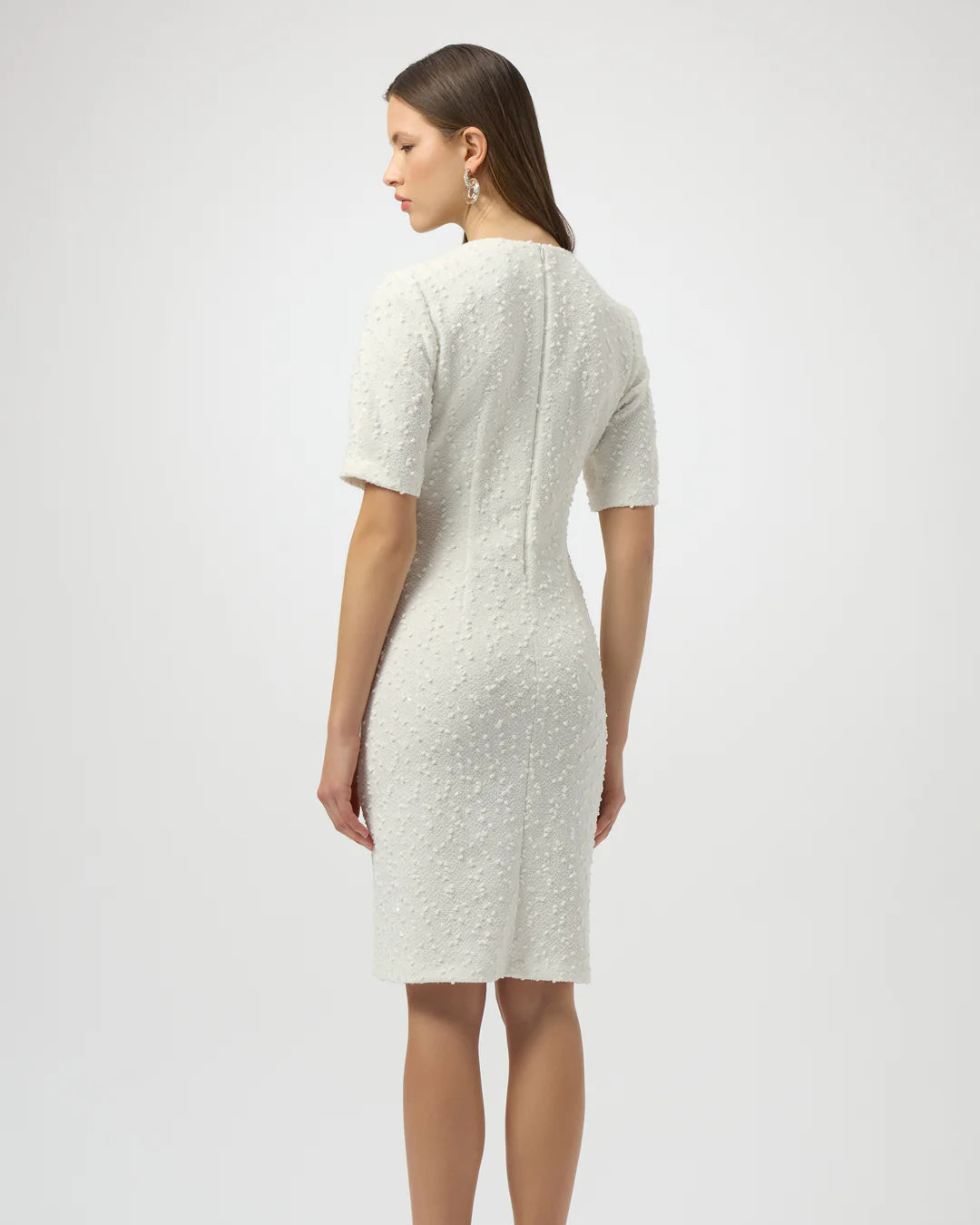 Woman wearing a white textured dress on a plain background