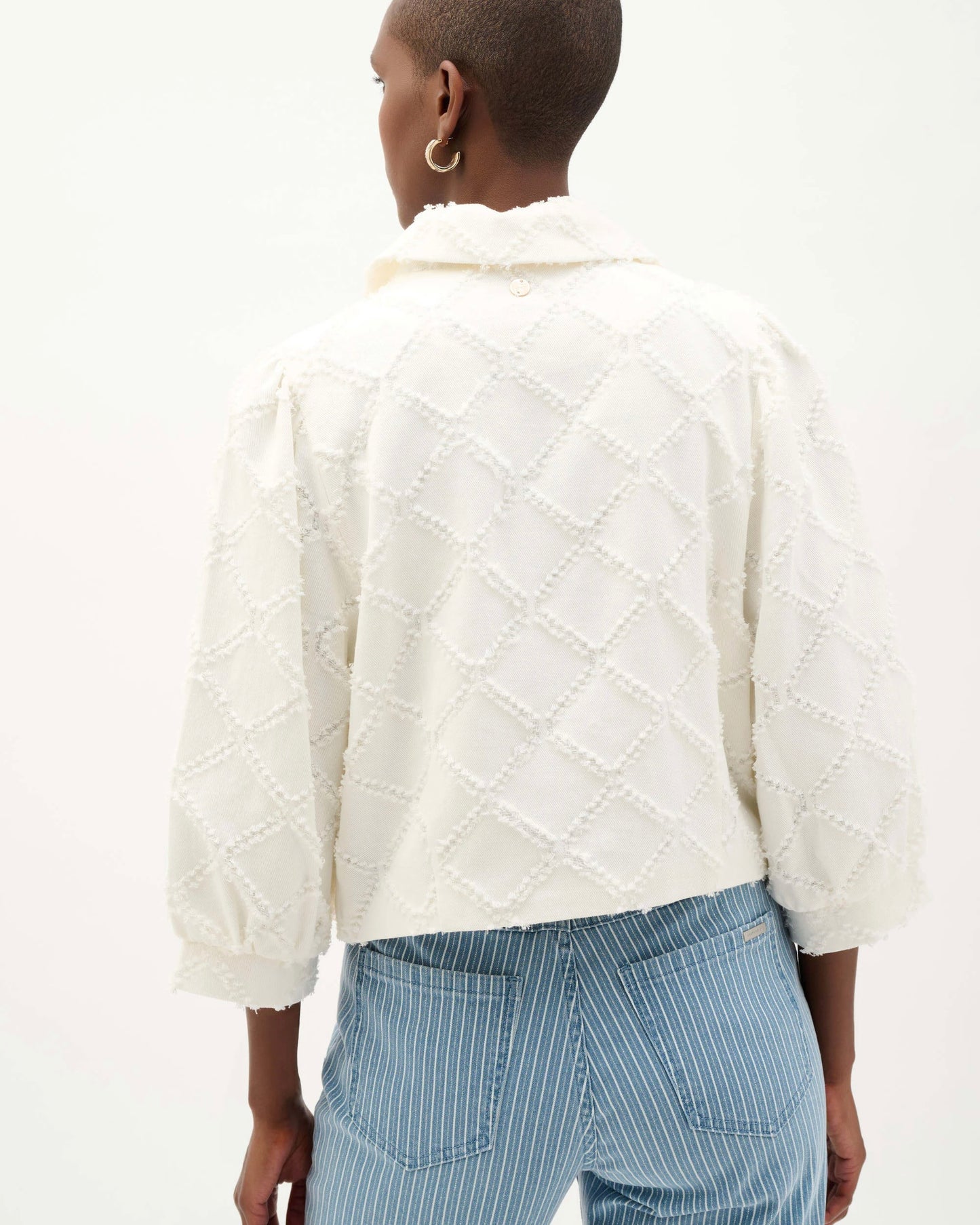 Person wearing a textured white sweater and blue striped pants on a white background