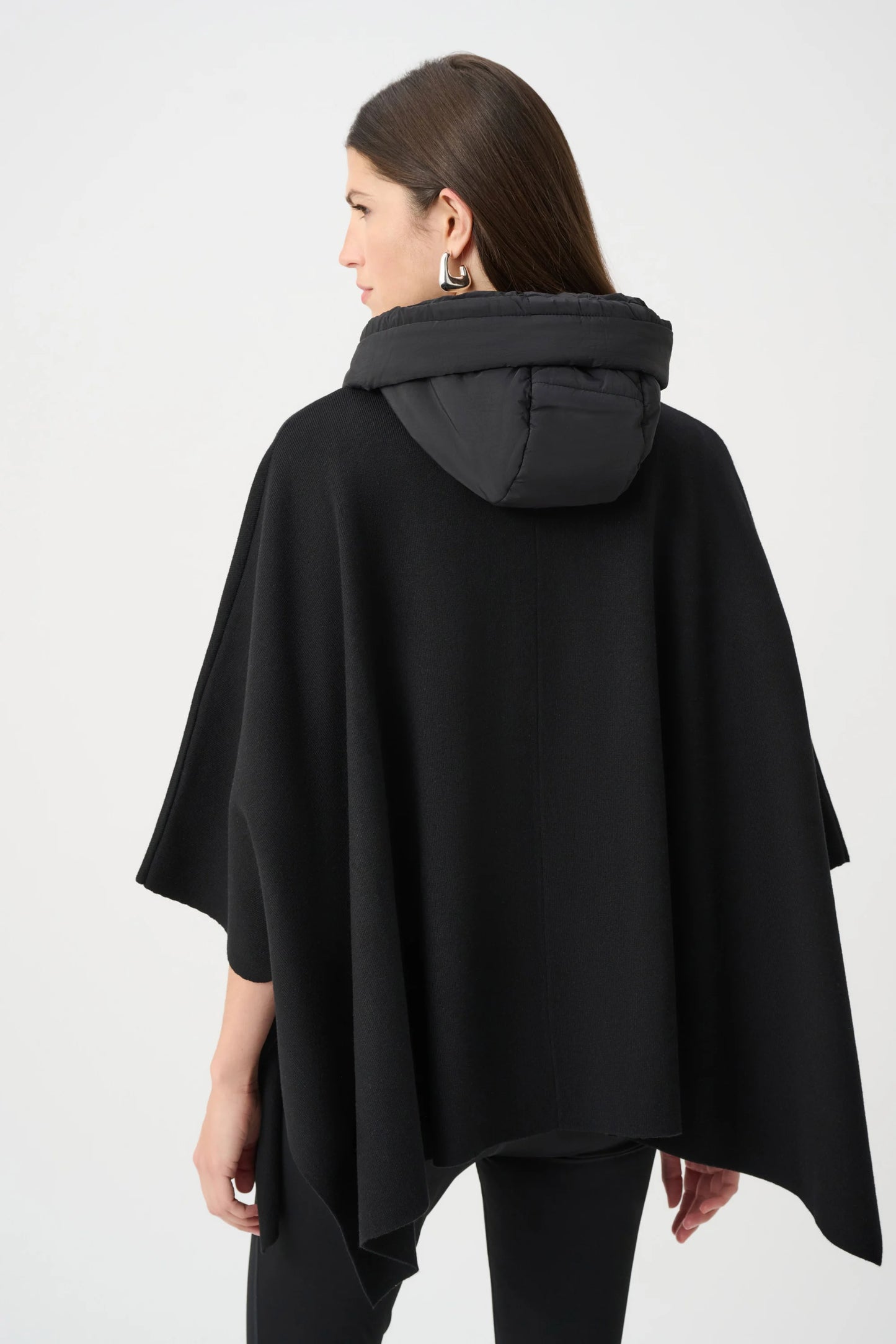 Woman wearing a black poncho with a hood on a white background