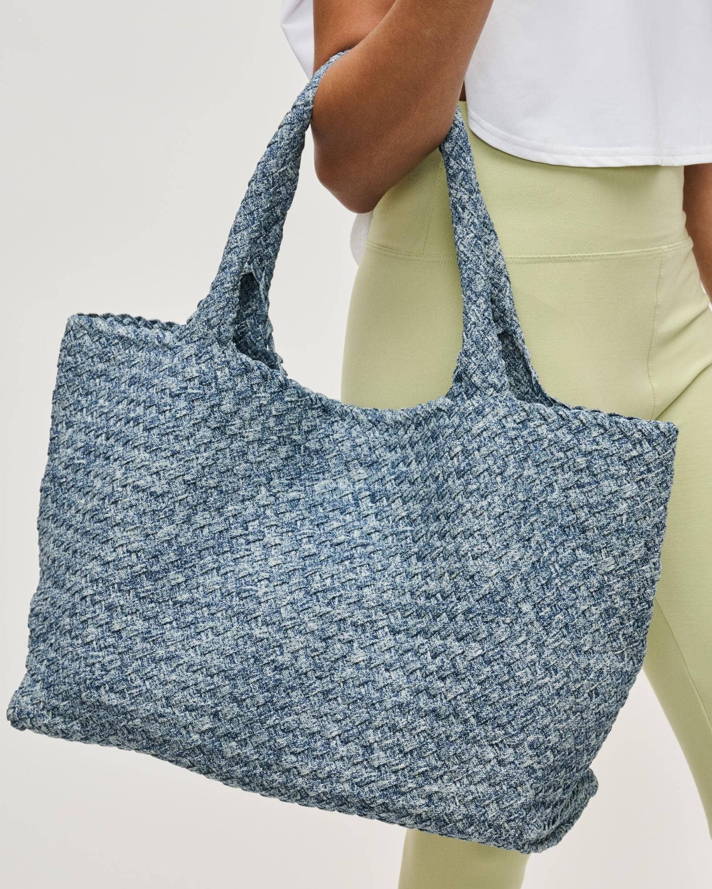 Person holding a blue textured tote bag against a plain background