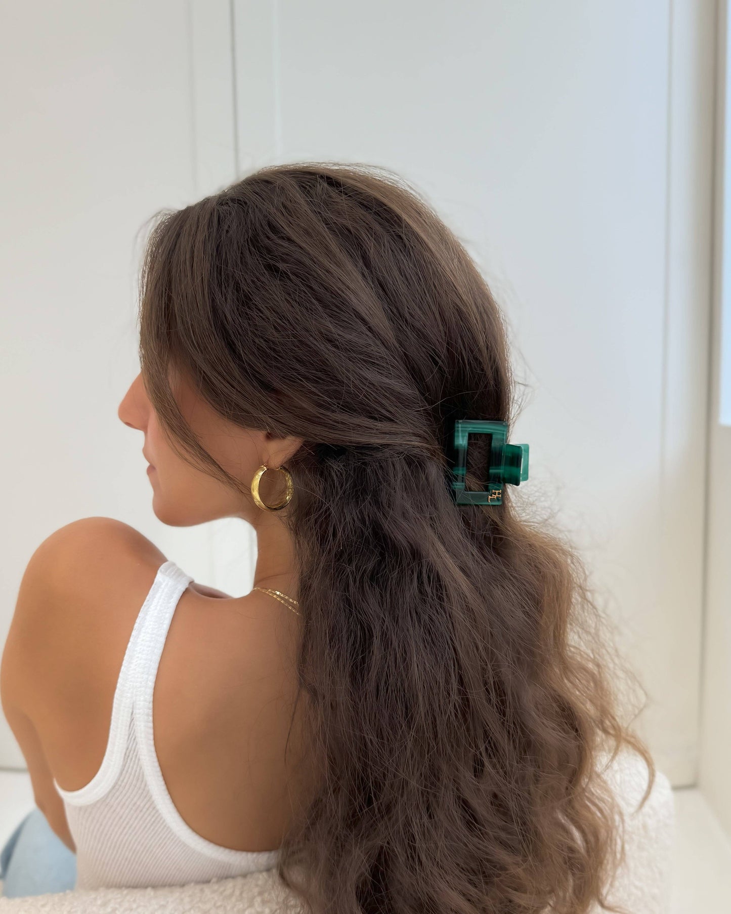 Woman with the HoneyLux Ecofriendly Acetate Midi Clip in Emerald in her hair, in front of a white wall