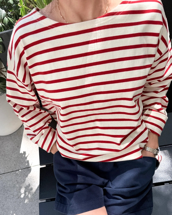 Person wearing a red and white striped shirt with navy shorts outdoors.