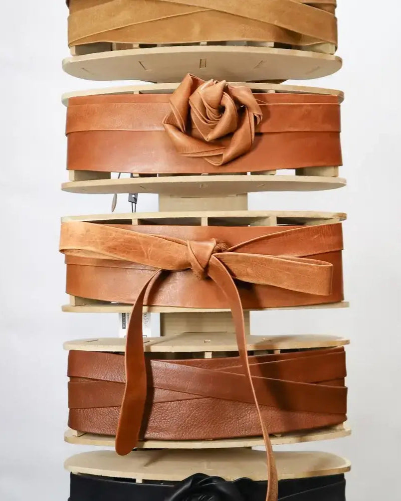 Stack of brown leather belts on a white background