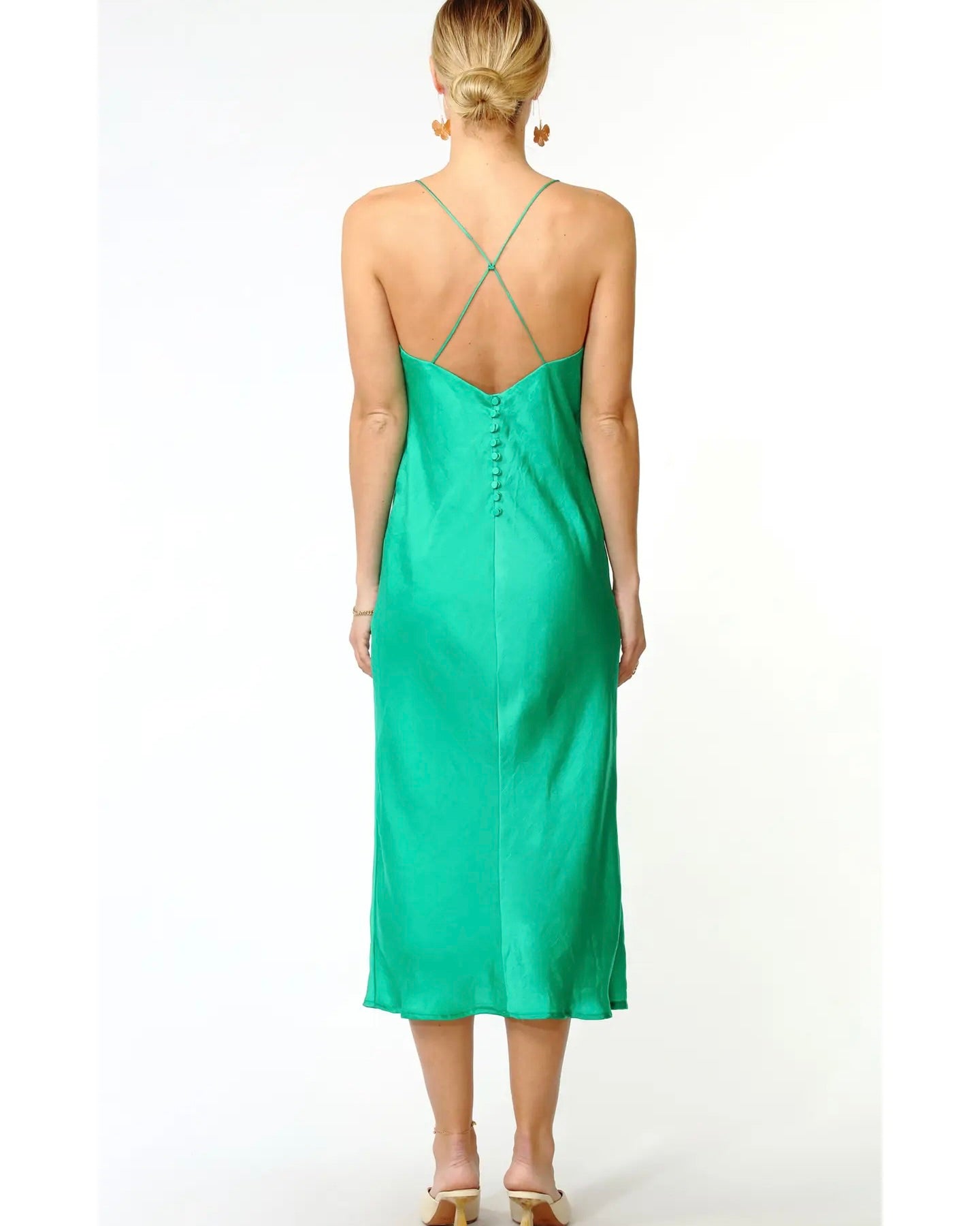 Back view of a model wearing the Greylin Sandra slip dress standing in front of a white background