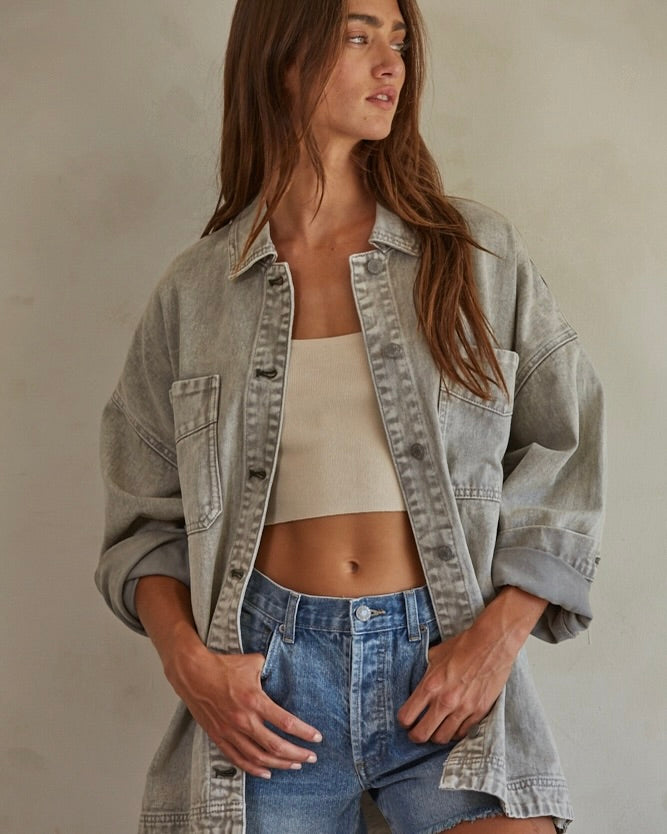 Close up photo of a model wearing the By Together Woven 100% Cotton Washed Denim Jacket in front of a beige wall