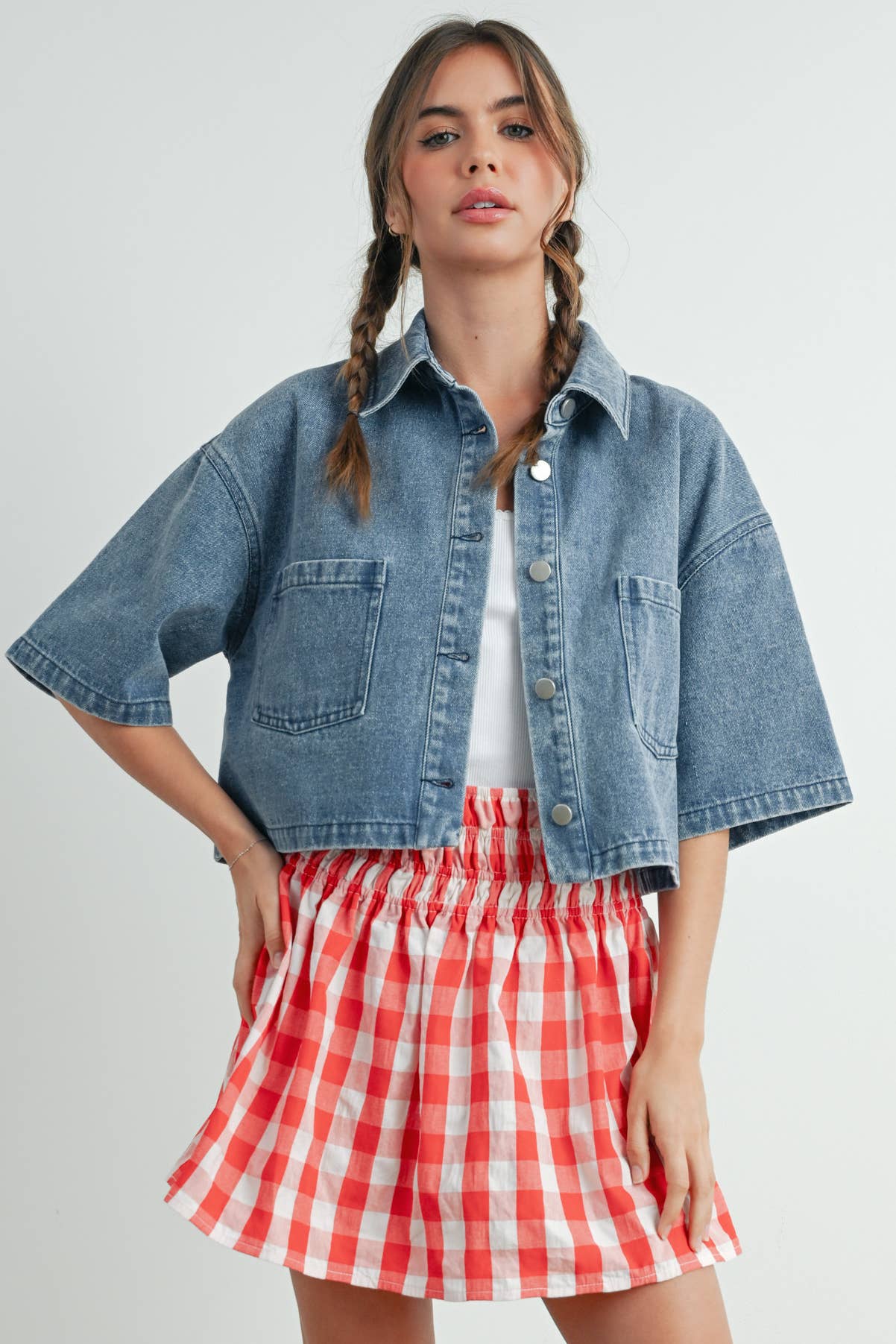 Woman wearing a denim jacket and red checkered skirt on a white background