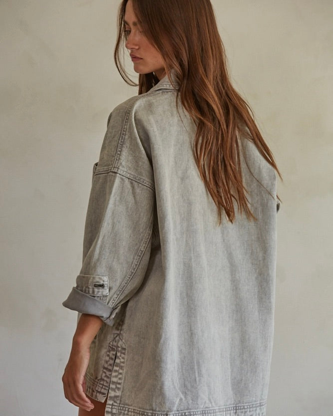 Back view of a model wearing the By Together Woven 100% Cotton Washed Denim Jacket in front of a beige wall