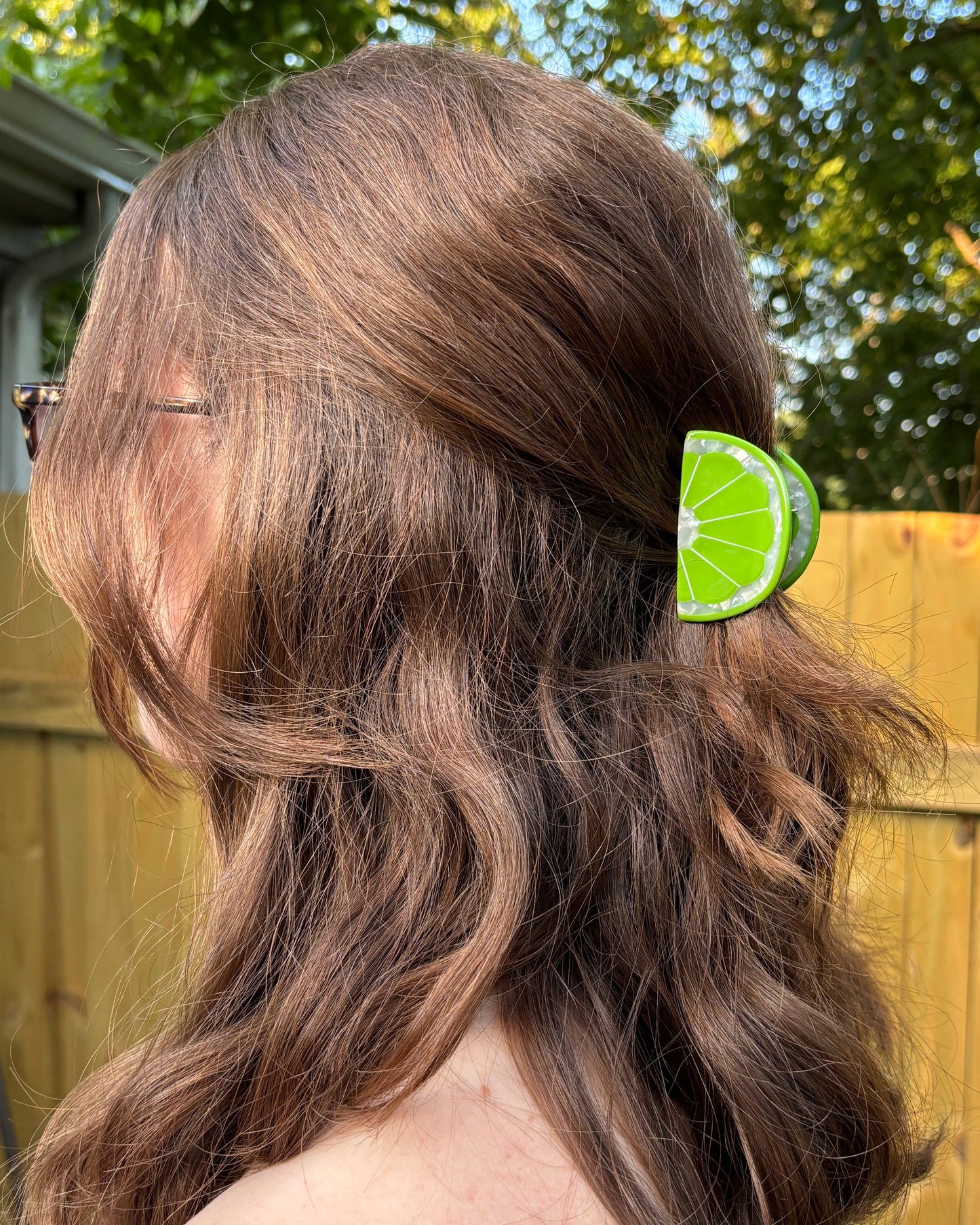 Person with wavy hair wearing a lime green hair clip outdoors