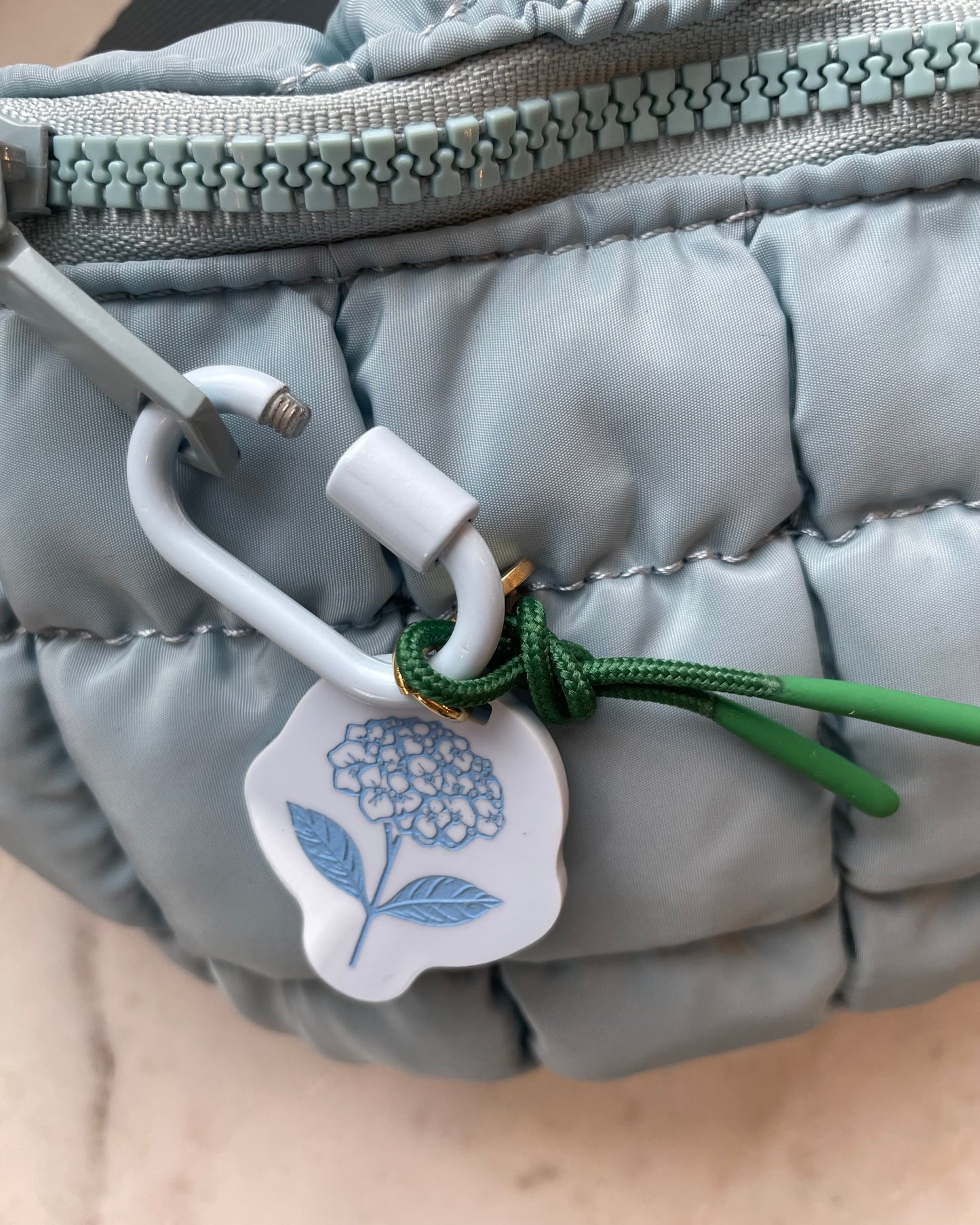 Freshwater curated goods hydrangea fish bag charm in front of sol and selene quilted bag in blue