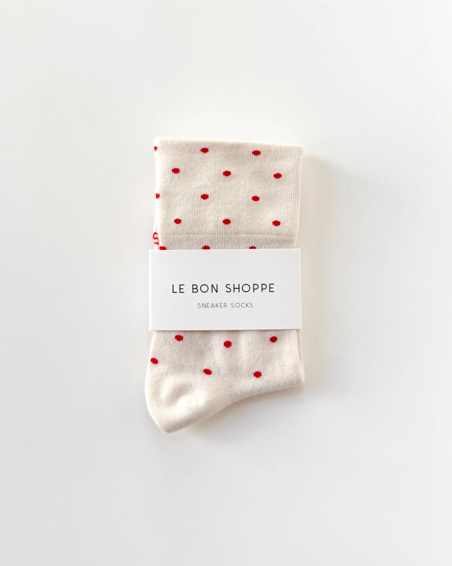 Pair of socks with red polka dots and a visible brand label on a white background