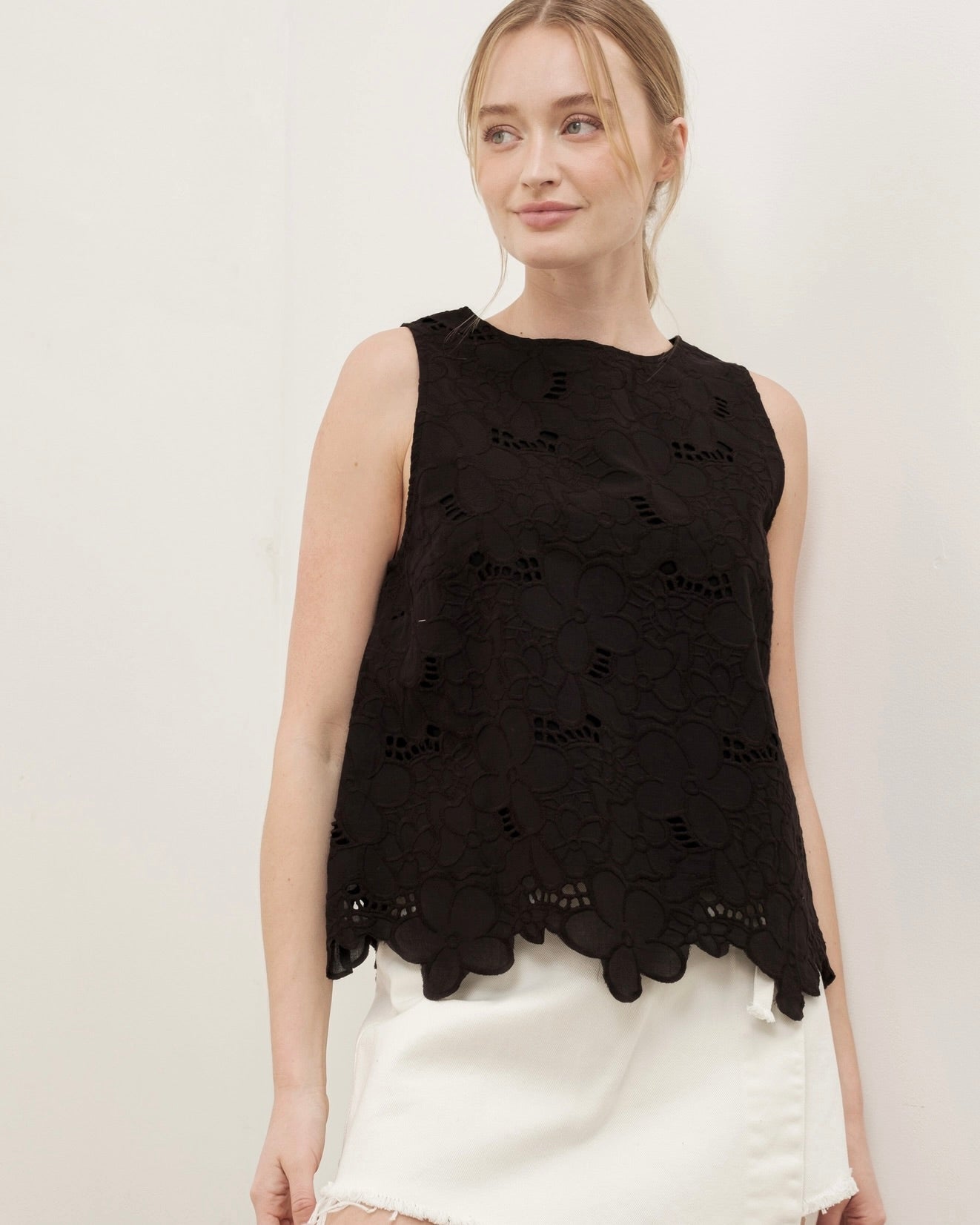 Photo of a model wearing the Flowered embroidered sleeveless top by Aaron & Amber standing in front of a white background