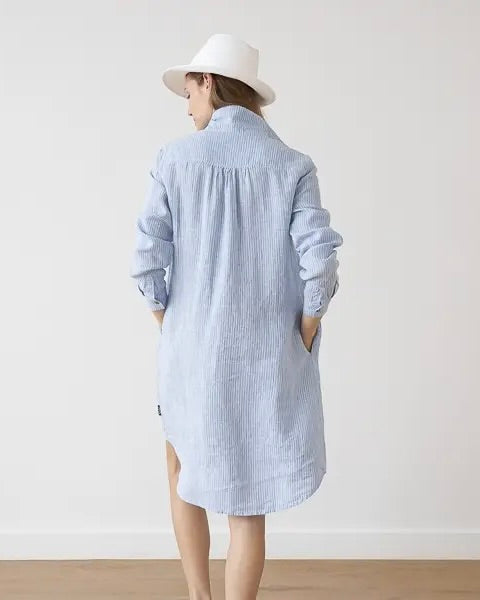 Back view of model wearing the LinenMe Linen Stripe Tee Dress in light blue with a white hat, standing against a white background