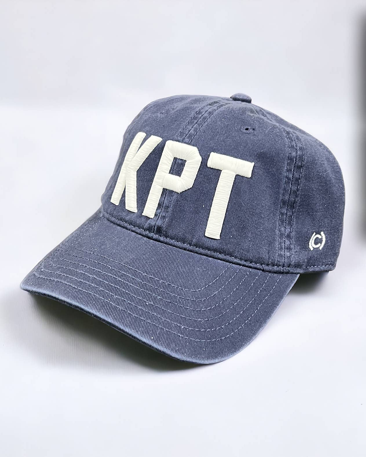 Blue cap with 'KPT' on a light gray background