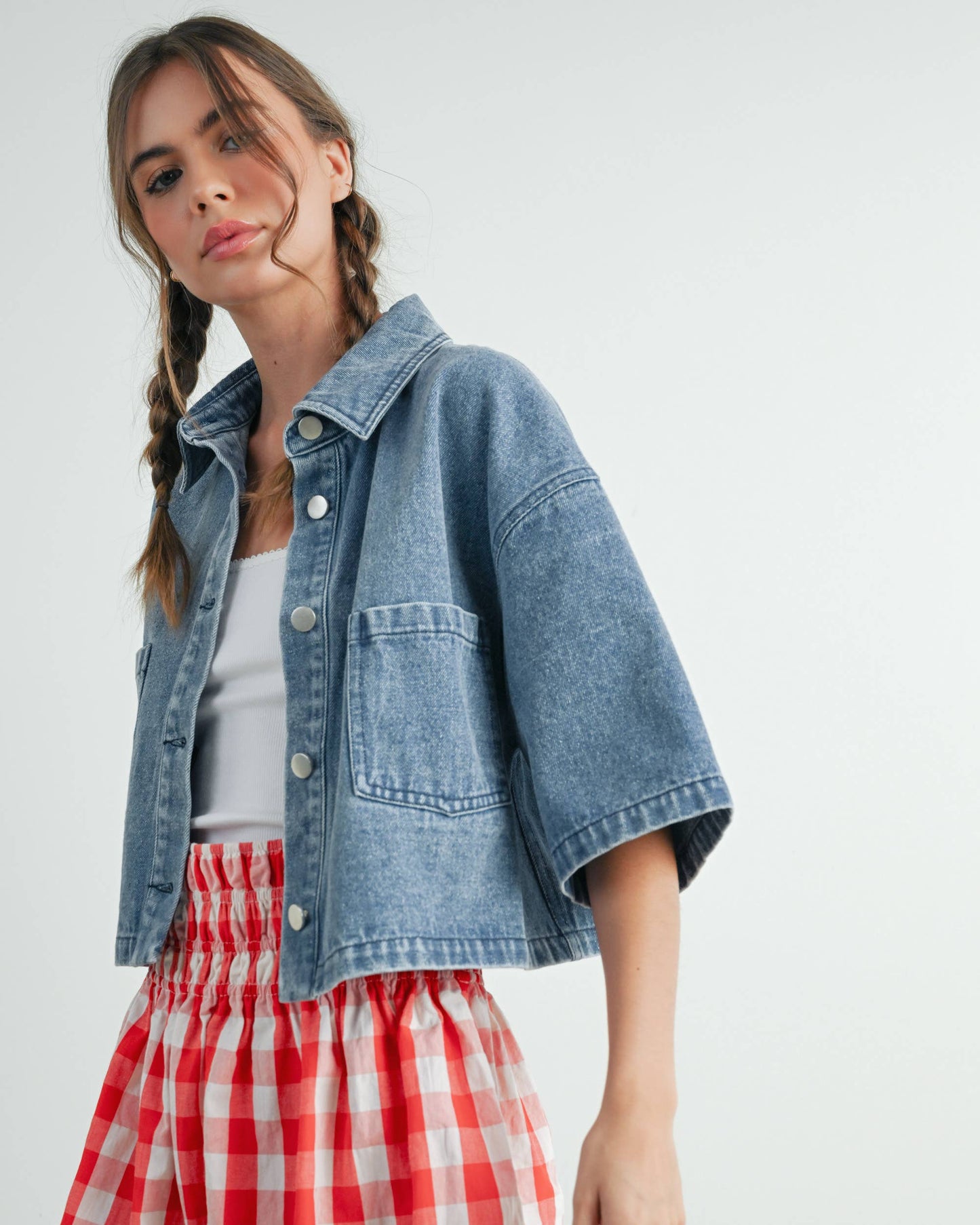 Woman wearing a denim jacket and red checkered skirt on a white background