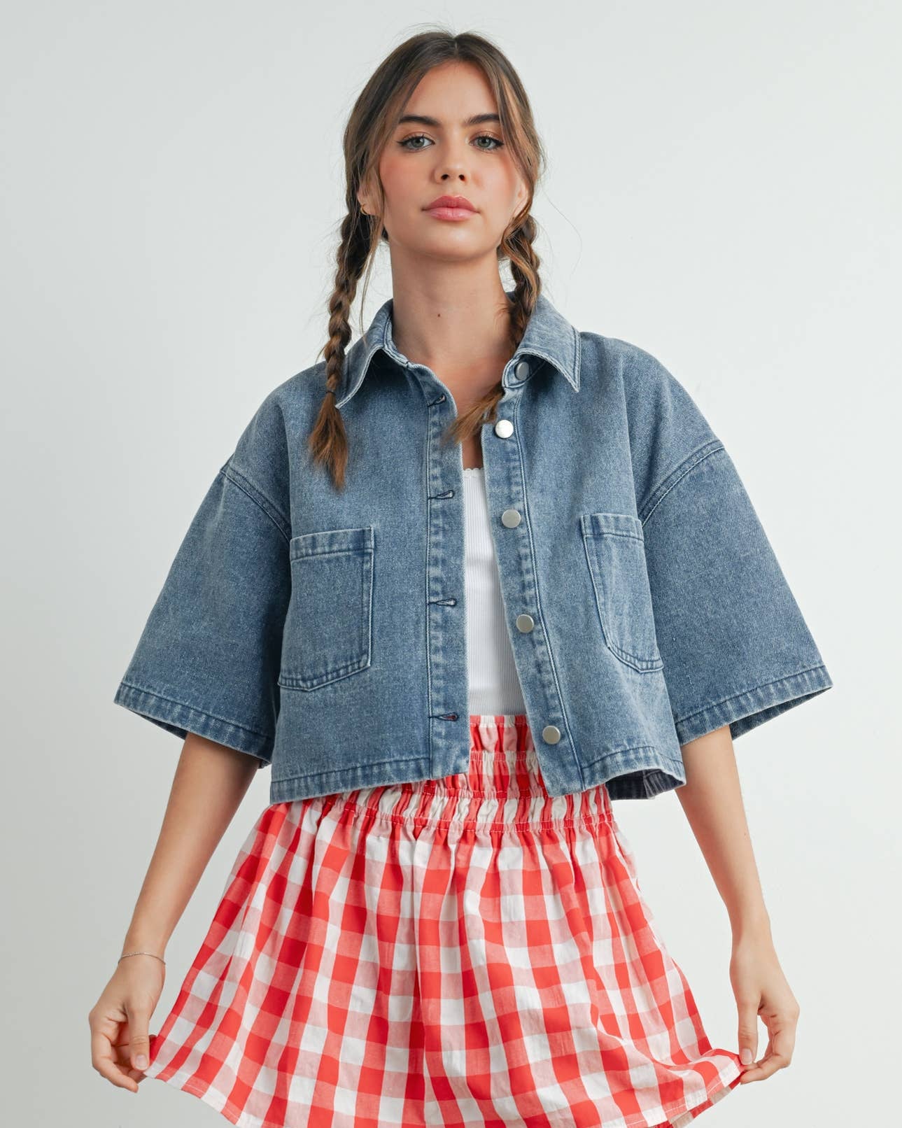 Woman wearing a denim jacket and red checkered skirt on a white background