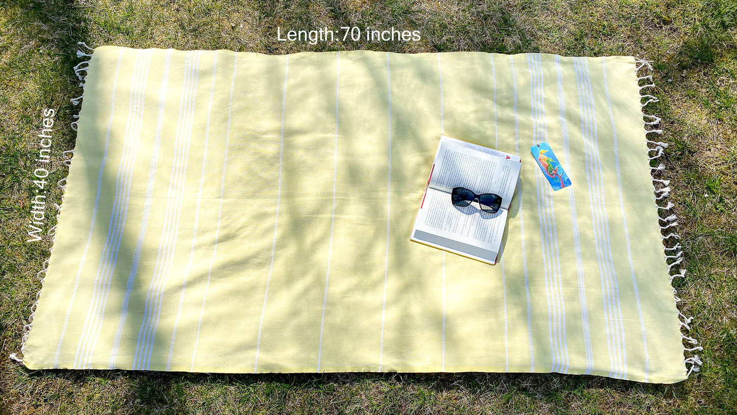 Yellow striped blanket on grass with a book and sunglasses on top, labeled 'Length: 70 inches'.