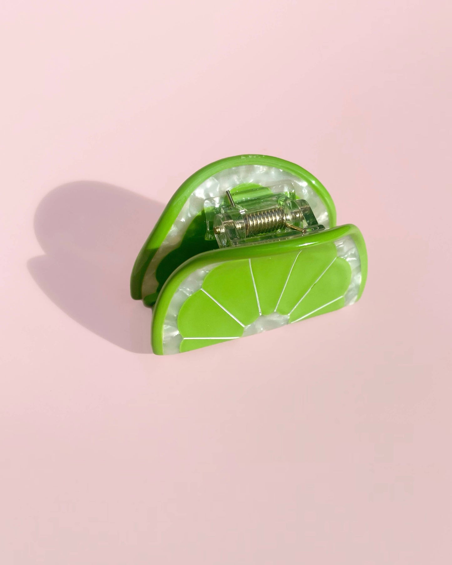 Green lime hair clip on a pink background