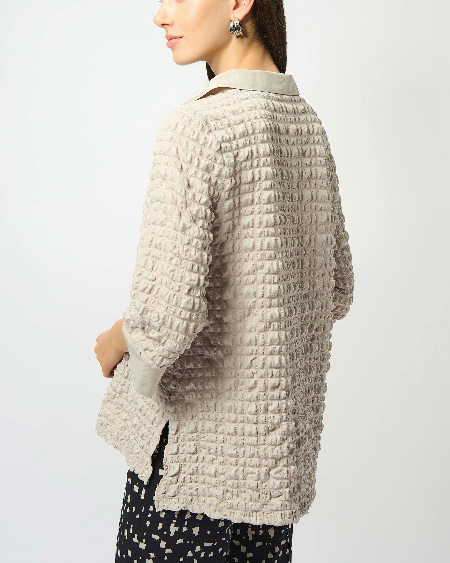 Model is wearing Joseph Ribkoff Bubble Jacquard A-Line Top in color moonstone with tan and black pants on a white background