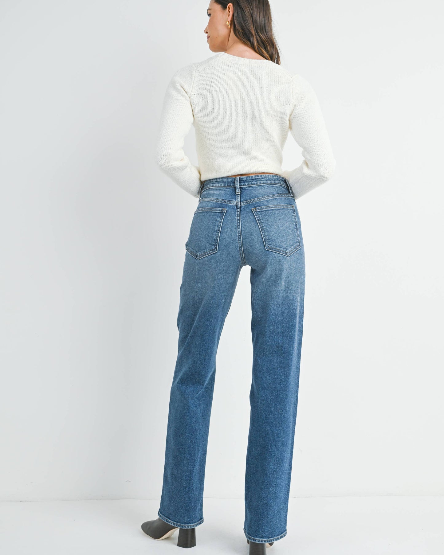 Person wearing blue jeans and a white top on a white background