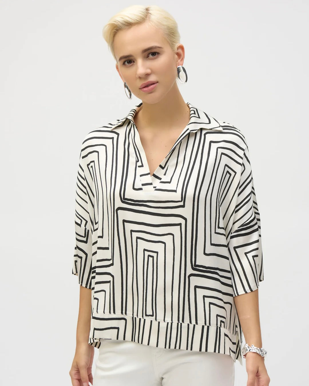 joseph ribkoff geometric boxy top on model in white jeans standing in front of white wall